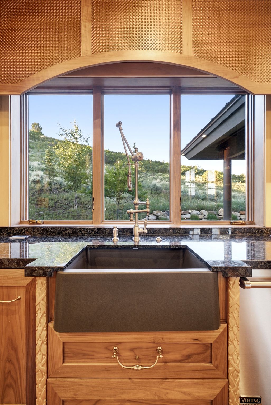 Farmhouse sink with a vintage-style faucet, set into dark granite countertops
