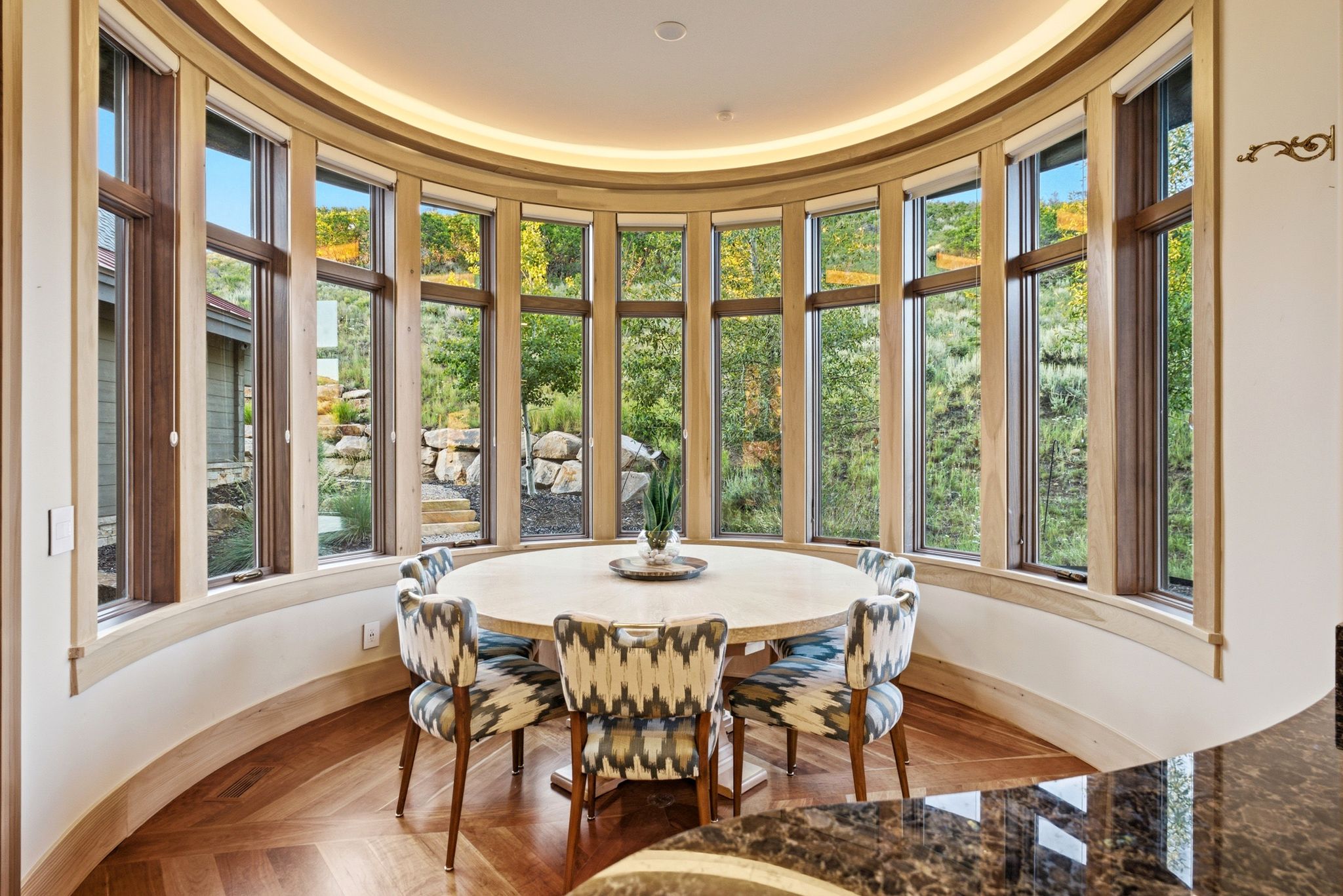 Curved architectural wall featuring a series of tall windows with natural wood trim, recessed ceiling lighting, and wood-finish flooring with a herringbone pattern