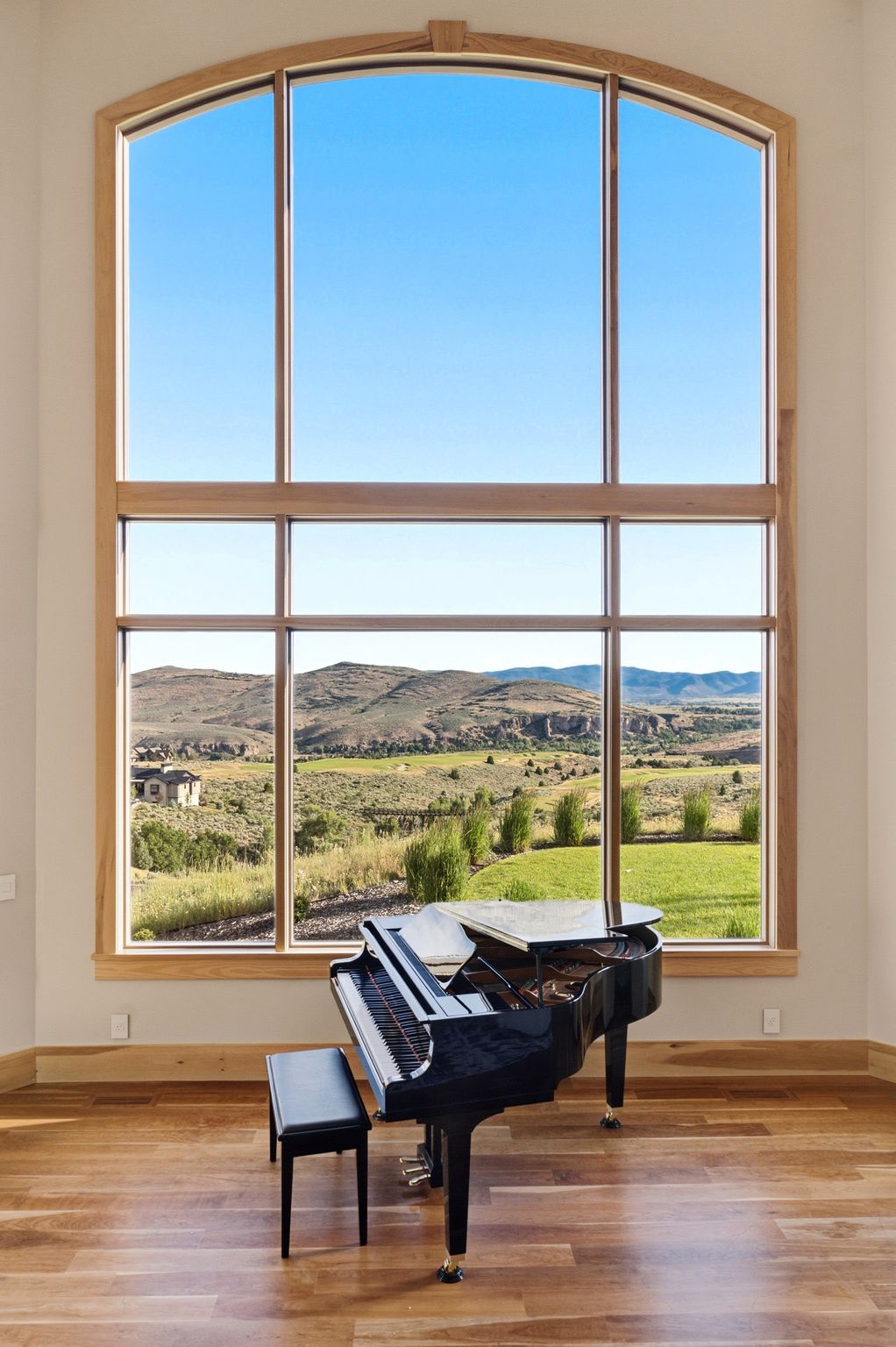 Two-story arched window featuring light wood trim