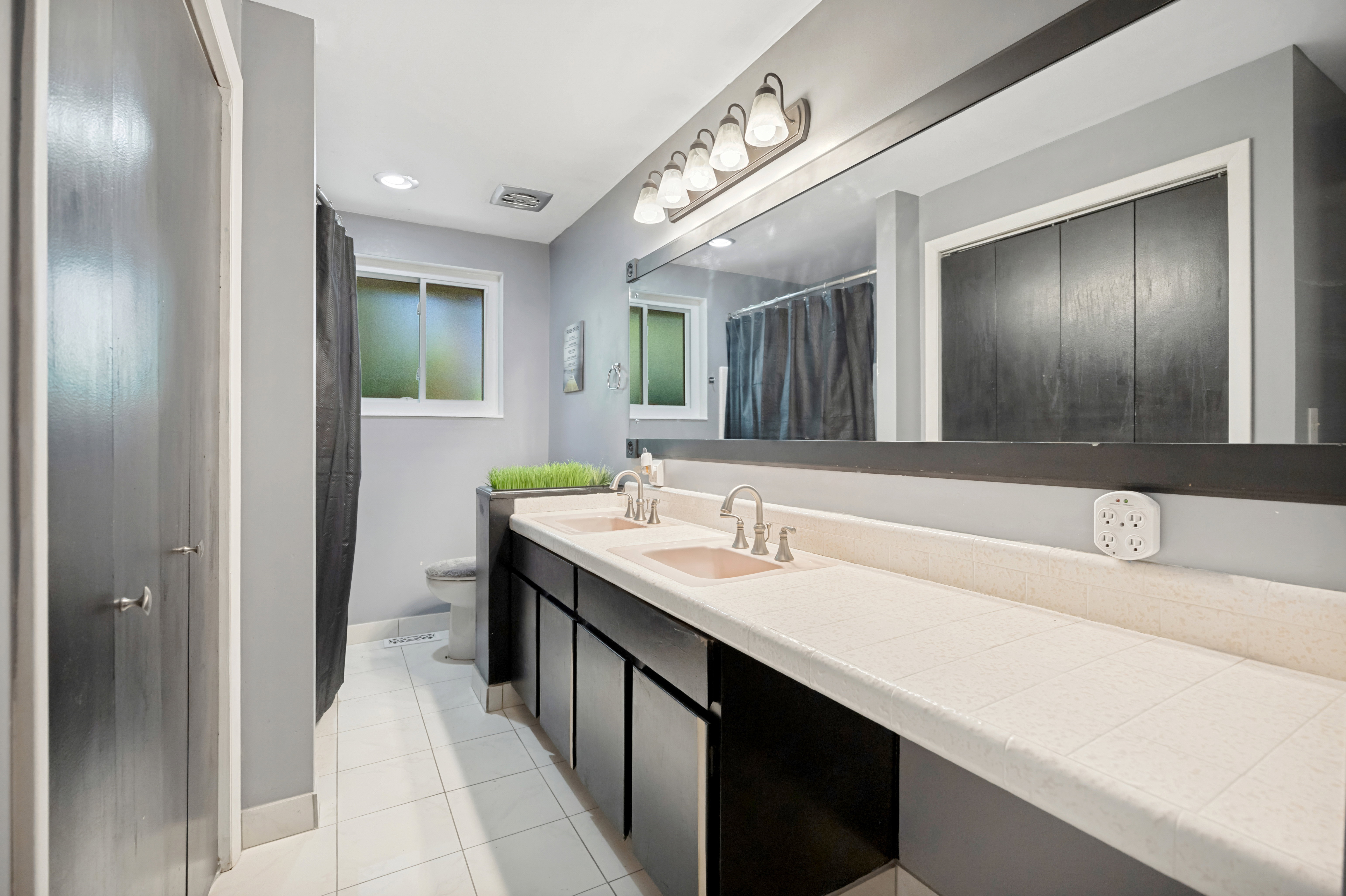Spacious bathroom featuring a dual vanity with integrated sinks and a large wall-mounted mirror