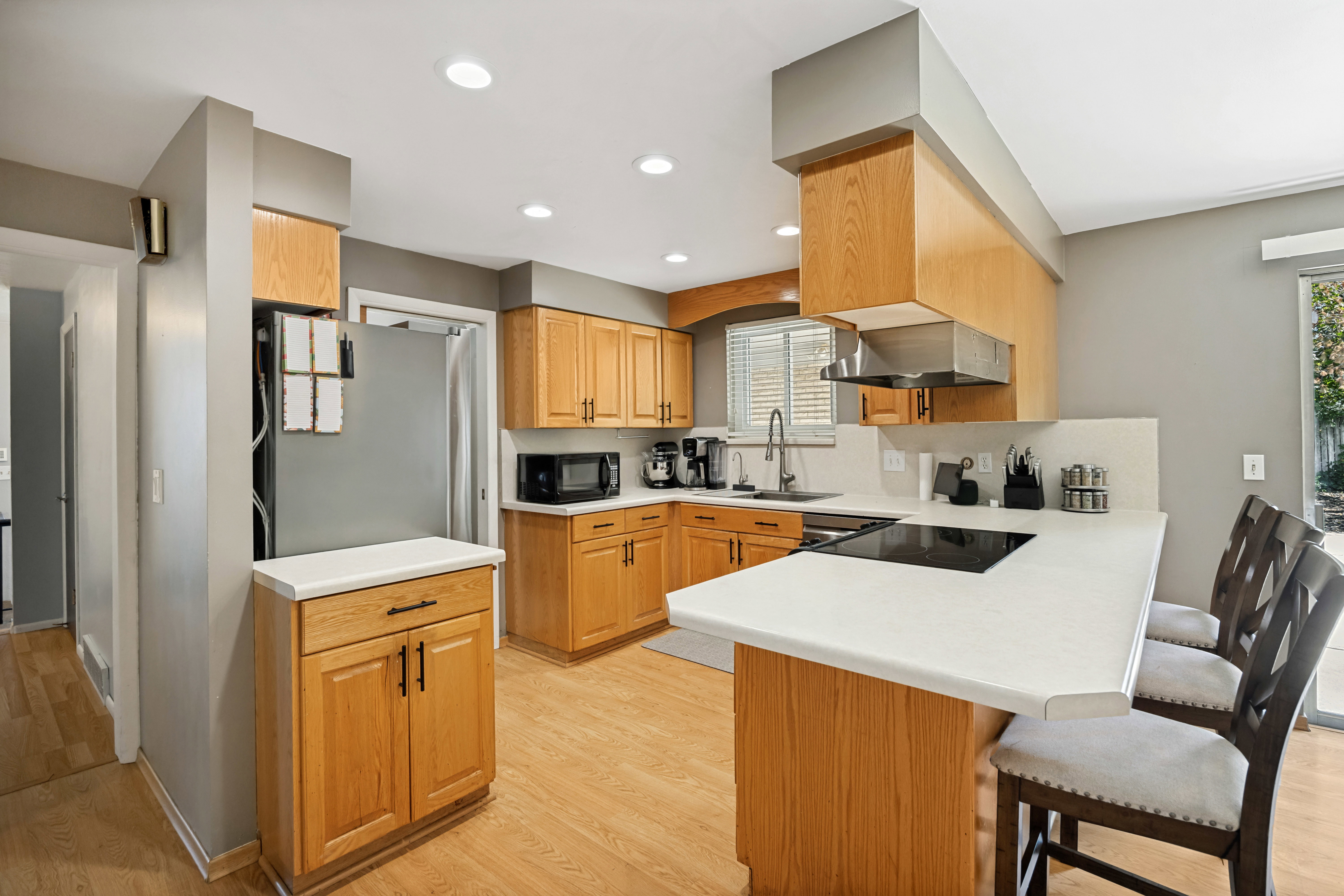 Kitchen featuring light wood cabinetry, white countertops, stainless steel appliances, wood-finish flooring, and recessed lighting
