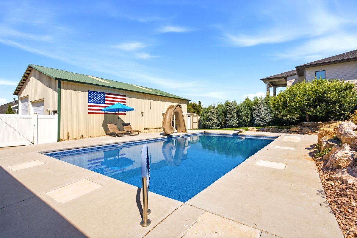 Rectangular in-ground swimming pool with an integrated slide and surrounding concrete decking