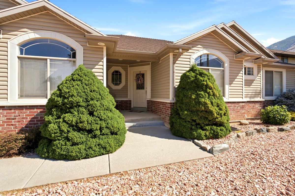 Front exterior featuring beige horizontal siding and a red brick foundation