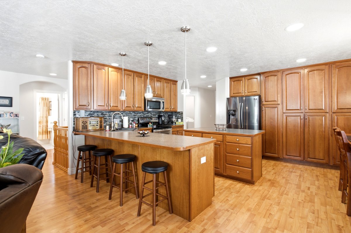 Kitchen featuring wood-finish flooring, abundant cabinetry, stainless steel appliances, a kitchen island with seating, and pendant lighting