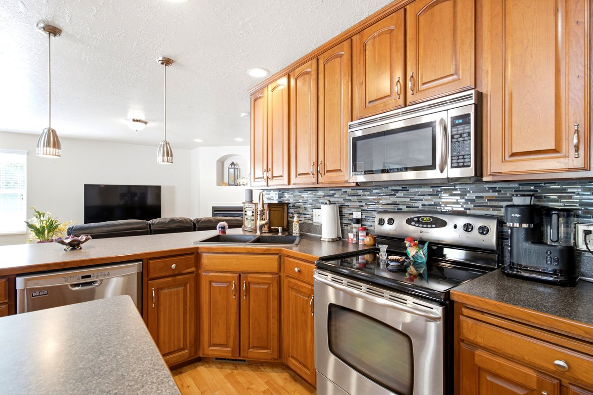 Kitchen featuring wood-finish cabinetry, stainless steel appliances, and a mosaic tile backsplash