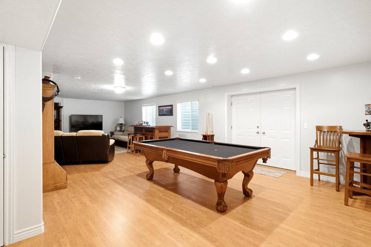 Spacious recreation room featuring wood-finish flooring, recessed lighting, and white double doors