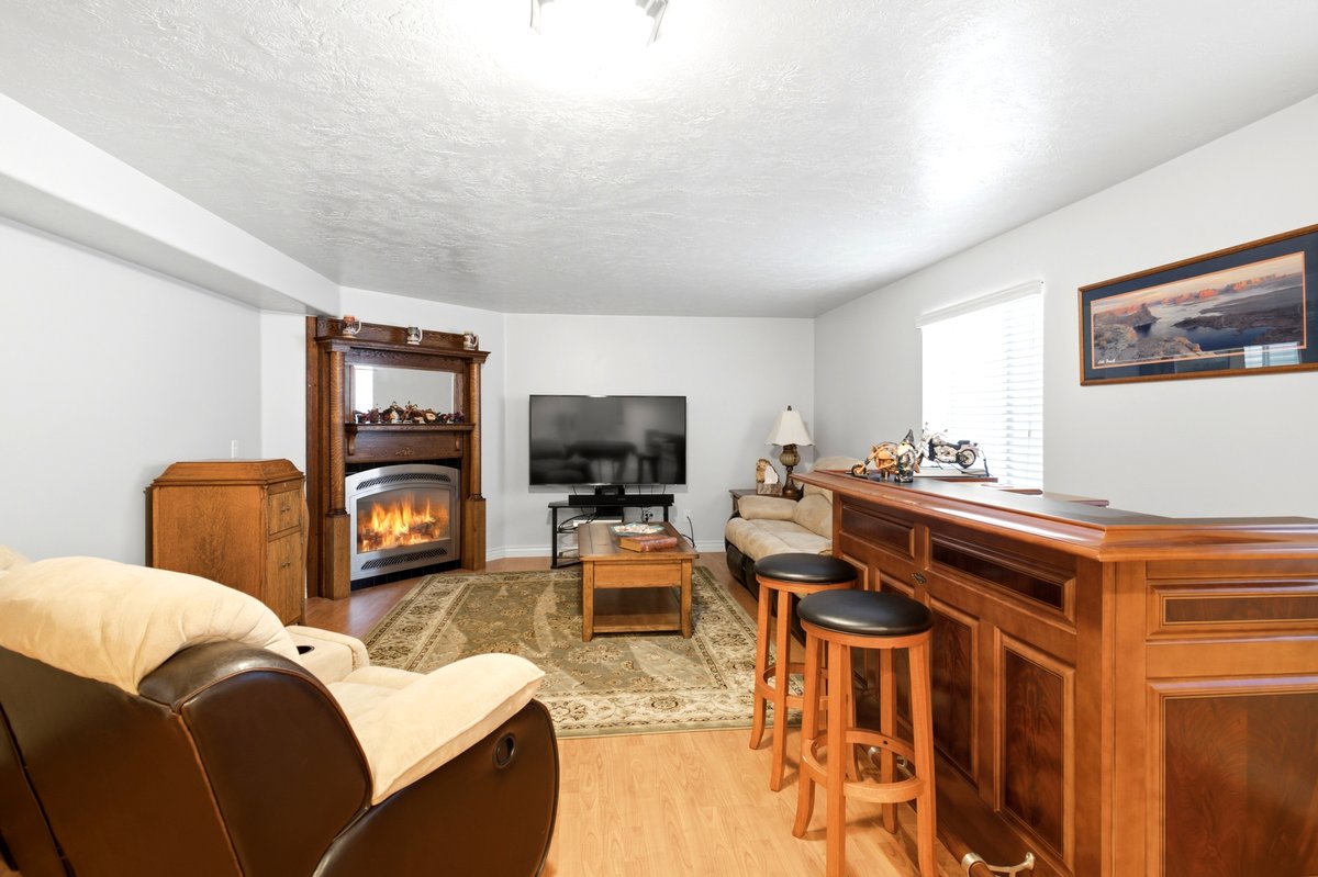 Recreational space featuring a built-in wood bar with seating, wood-finish flooring, and a decorative corner fireplace with an ornate wood mantel
