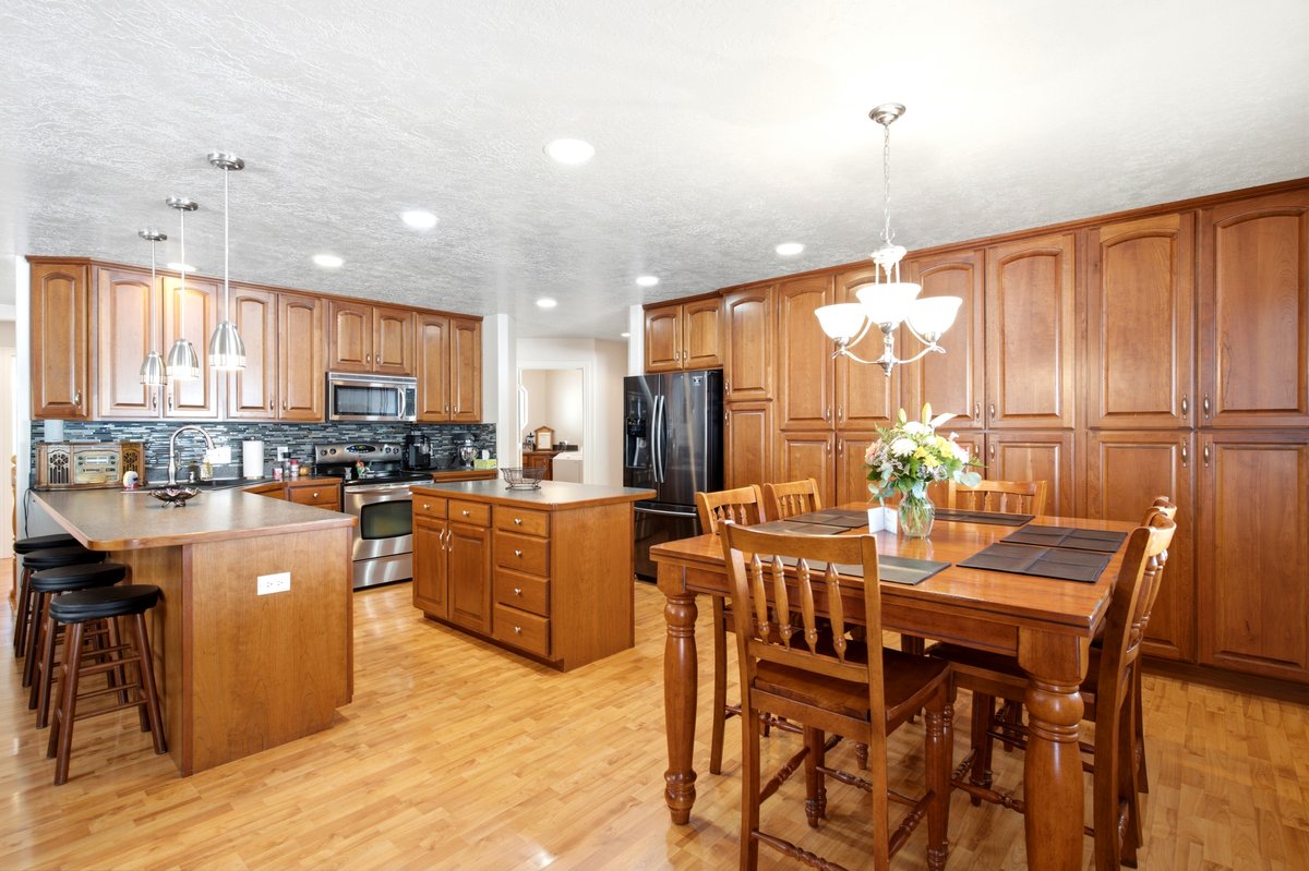 Spacious kitchen featuring extensive wood cabinetry, stainless steel appliances, a large island with pendant lighting, a central island, and wood-finish flooring