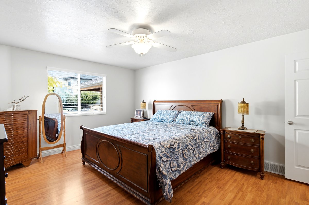 Room featuring wood-finish flooring, white walls, and a ceiling fan with integrated lighting