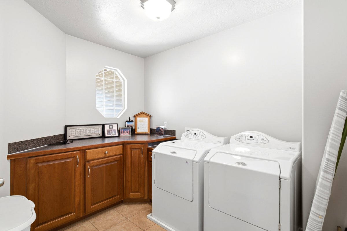Laundry area featuring a built-in wood cabinetry, a dark countertop, an octagonal window, and tiled flooring