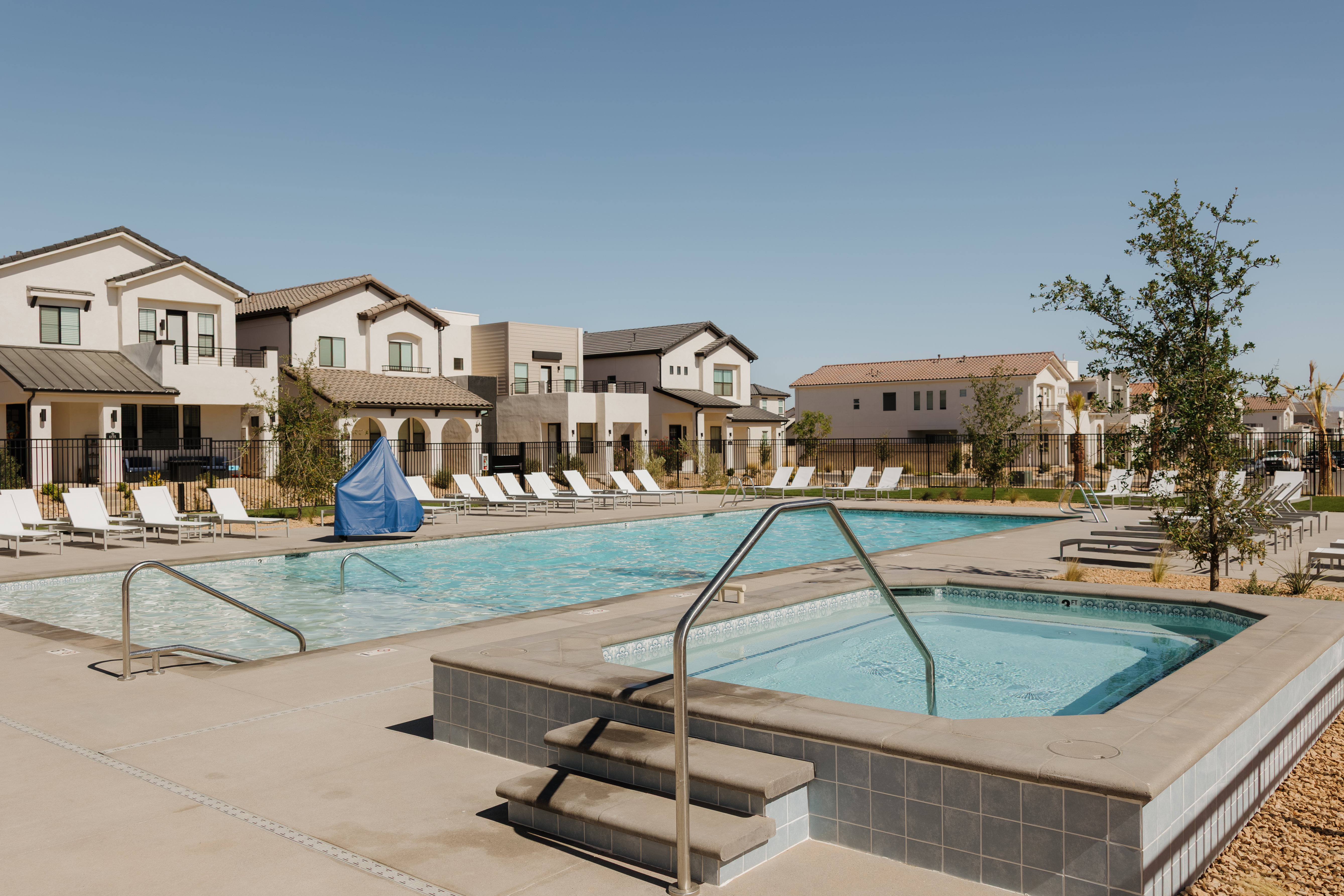 Resident Community swimming pool with an integrated spa, surrounded by a concrete deck and multiple lounge chairs