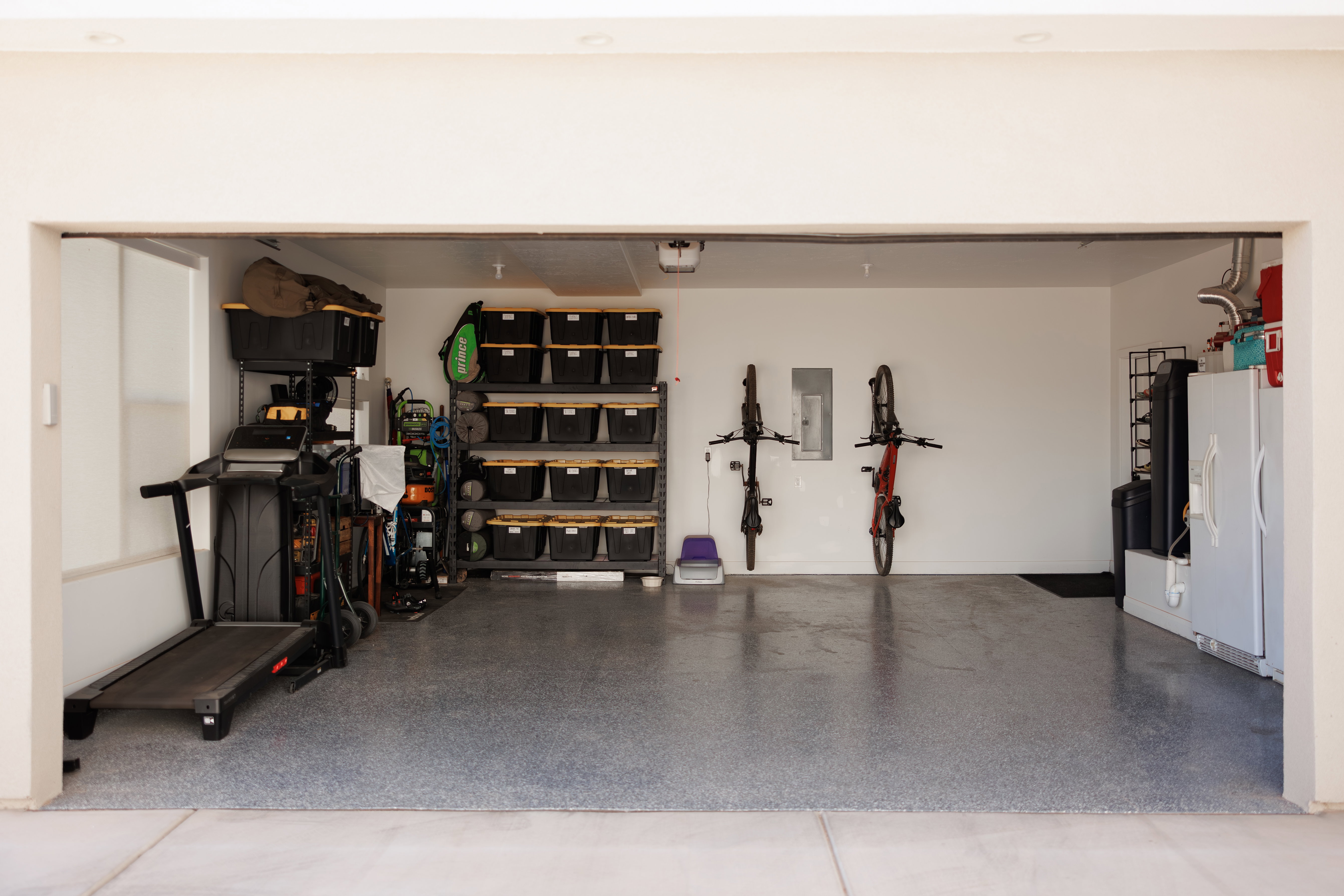 Spacious garage featuring a durable epoxy floor coating, white painted walls, and overhead lighting