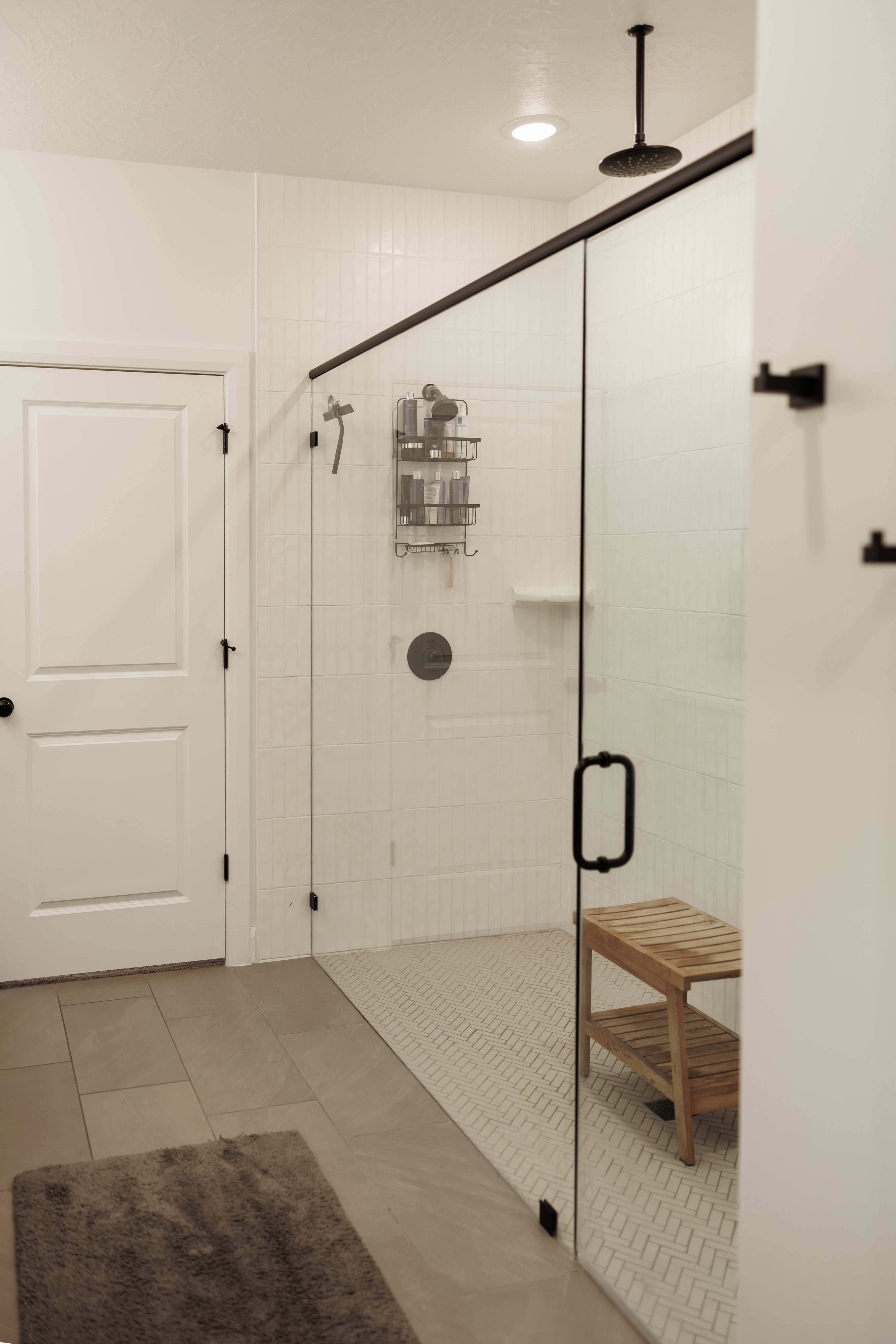 Glass-enclosed shower featuring white subway tile walls and a contrasting herringbone pattern tile floor