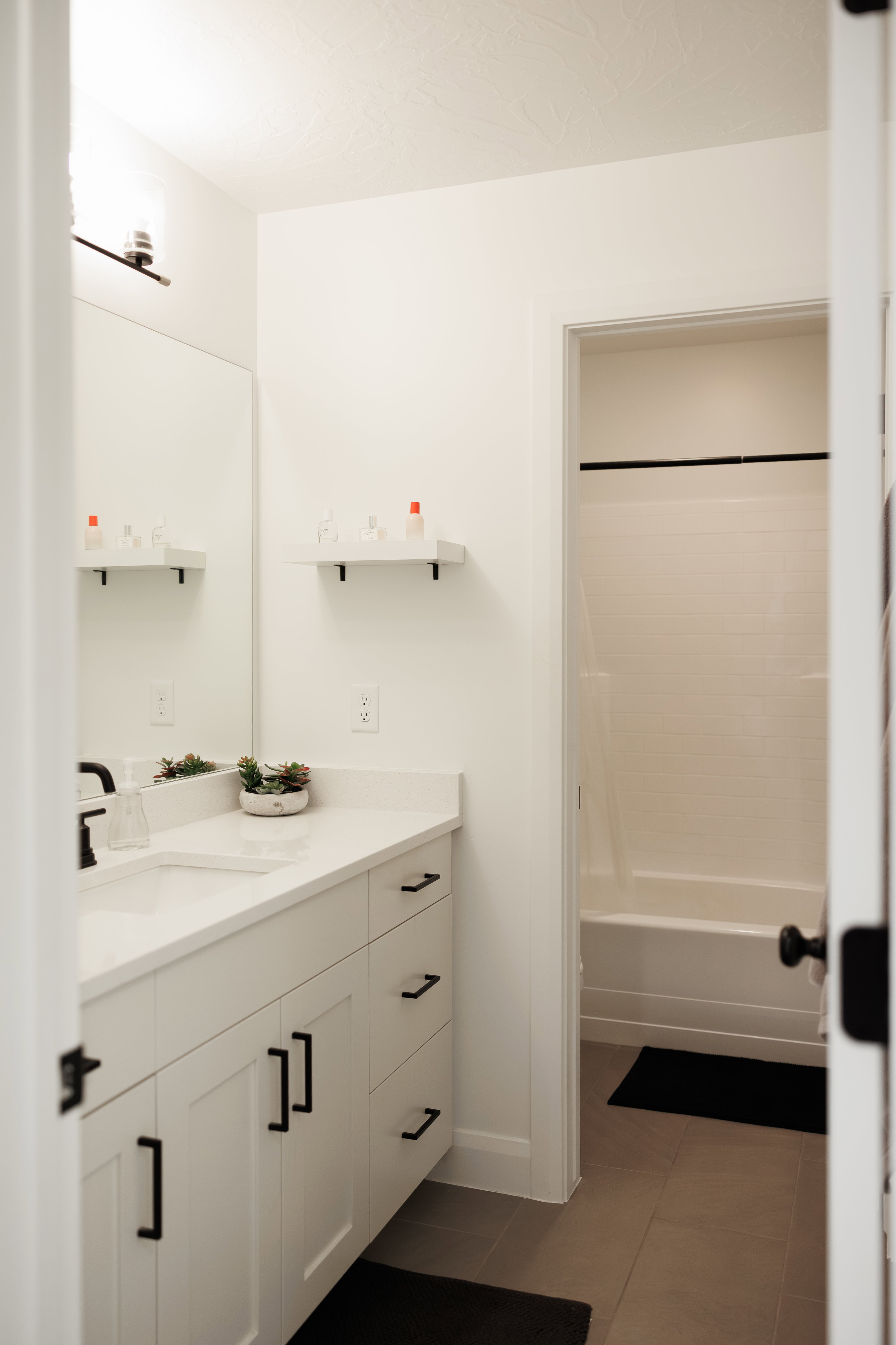 White vanity with black hardware, a rectangular undermount sink, and a light-toned countertop
