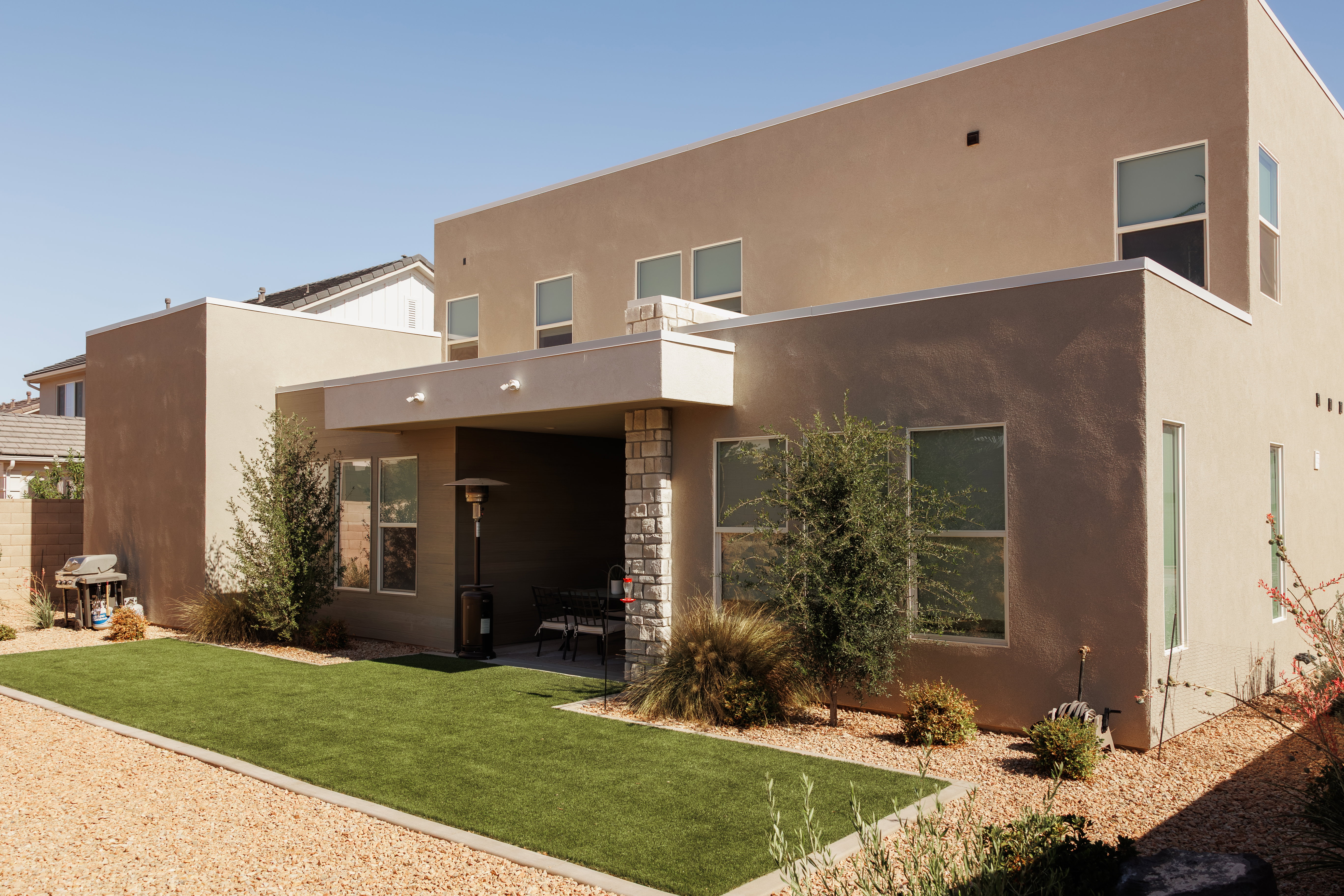 Contemporary stucco exterior featuring an integrated patio with stone-clad columns