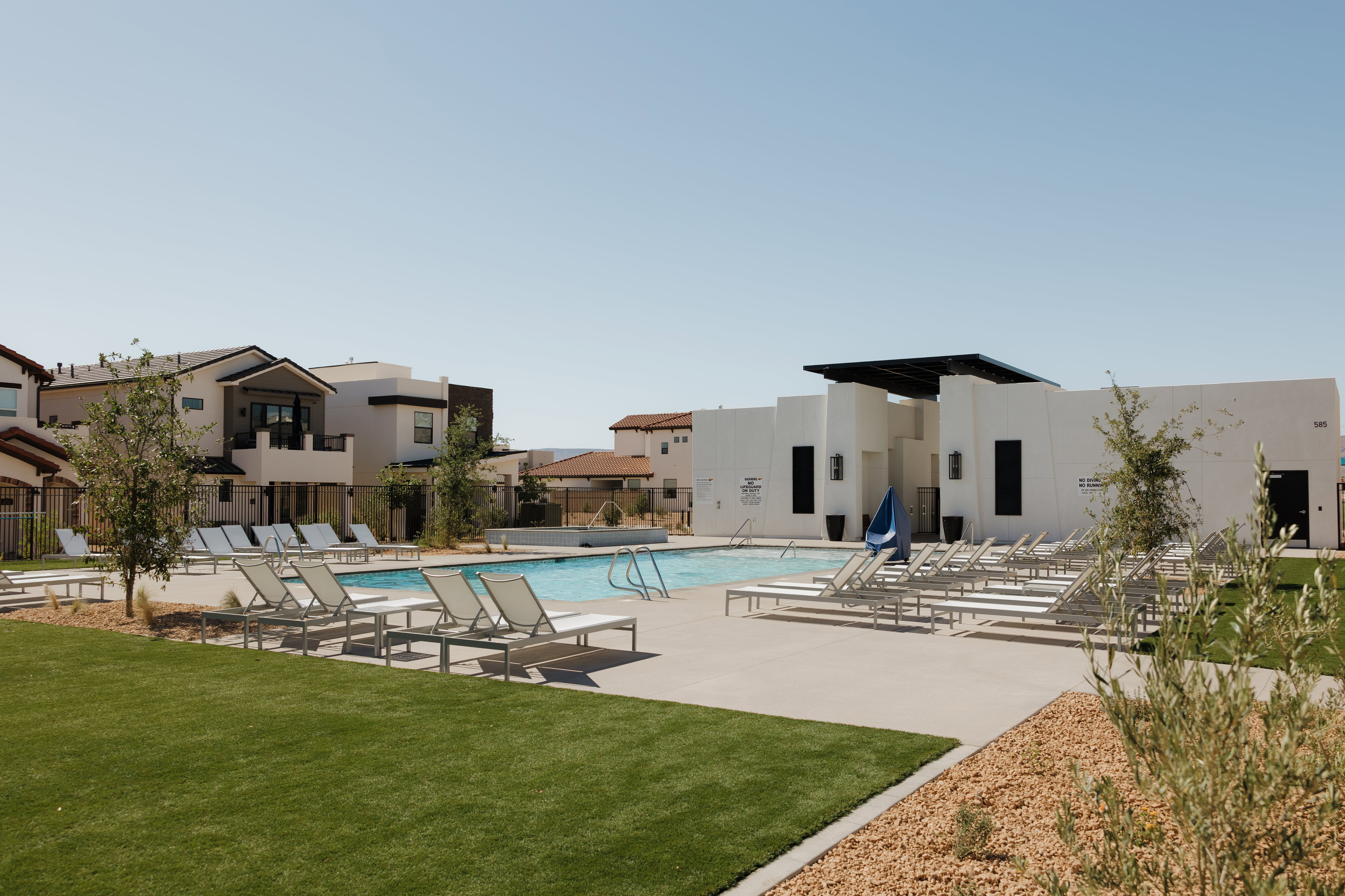 Resident Resort-style pool area featuring an expansive swimming pool with integrated steps, surrounding concrete decking, and numerous lounge chairs