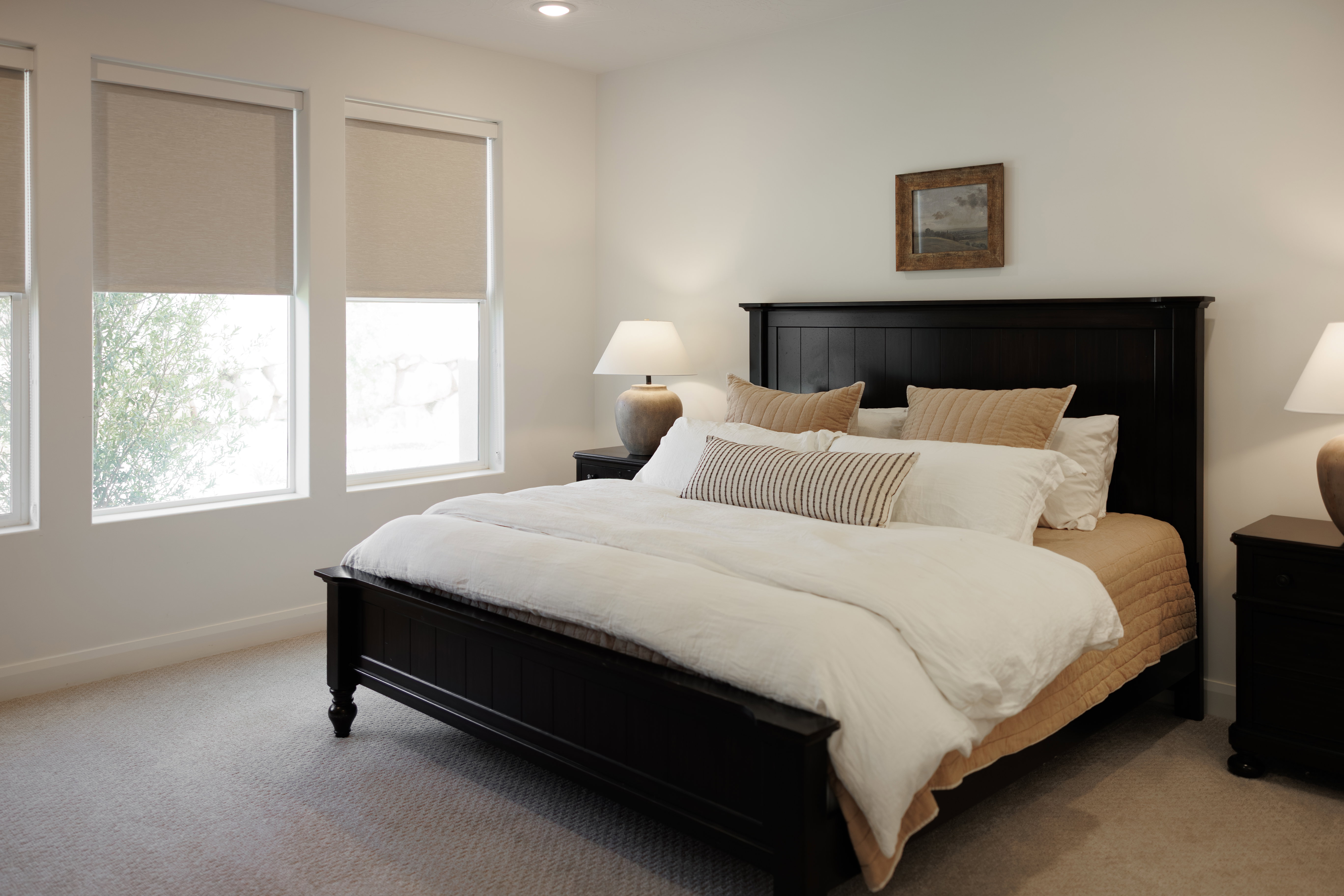 Bedroom featuring a dark wood bed frame, three large windows with roller shades, recessed lighting, and carpet flooring