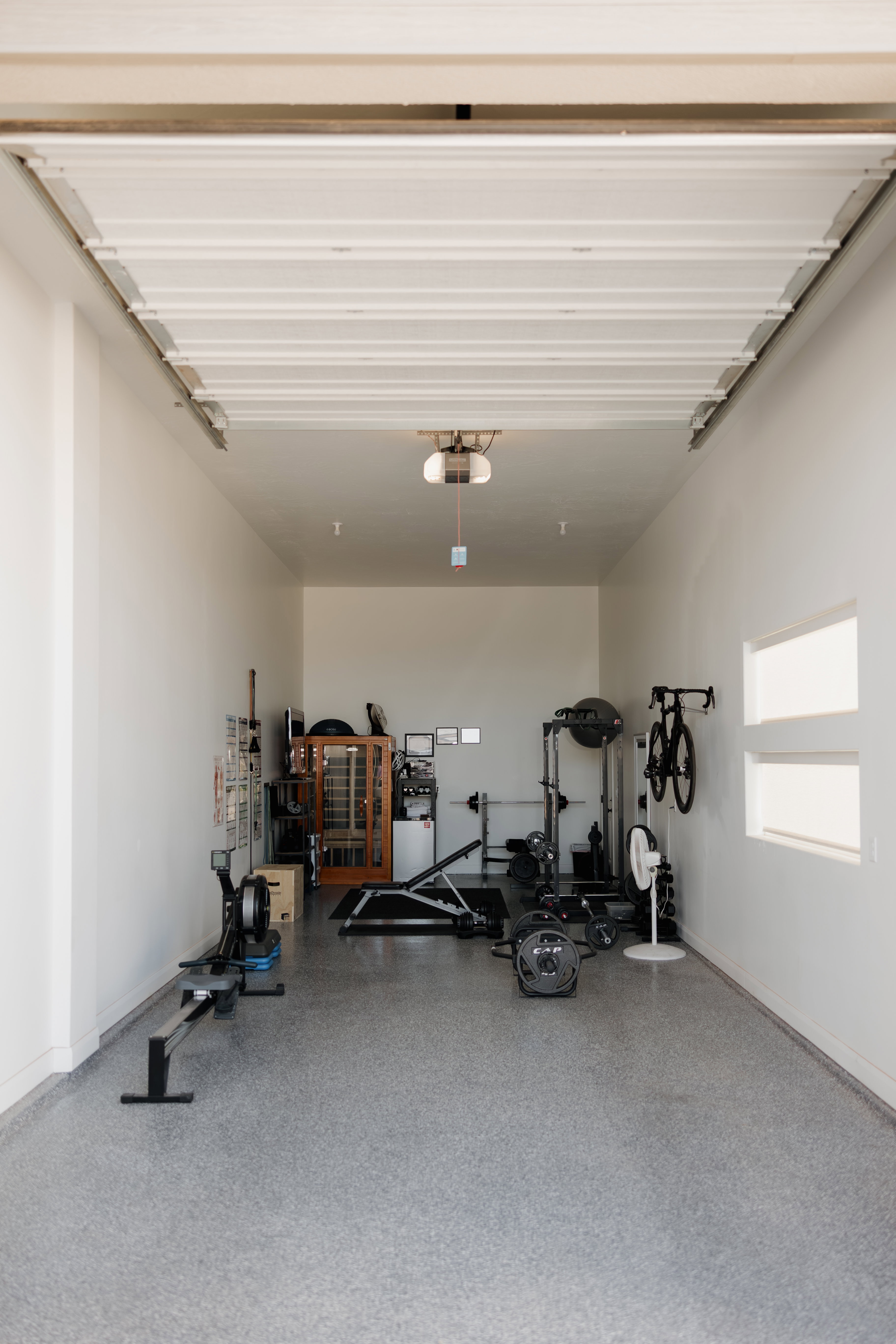 Spacious garage interior featuring a high ceiling, white painted walls, and an epoxy flake flooring system