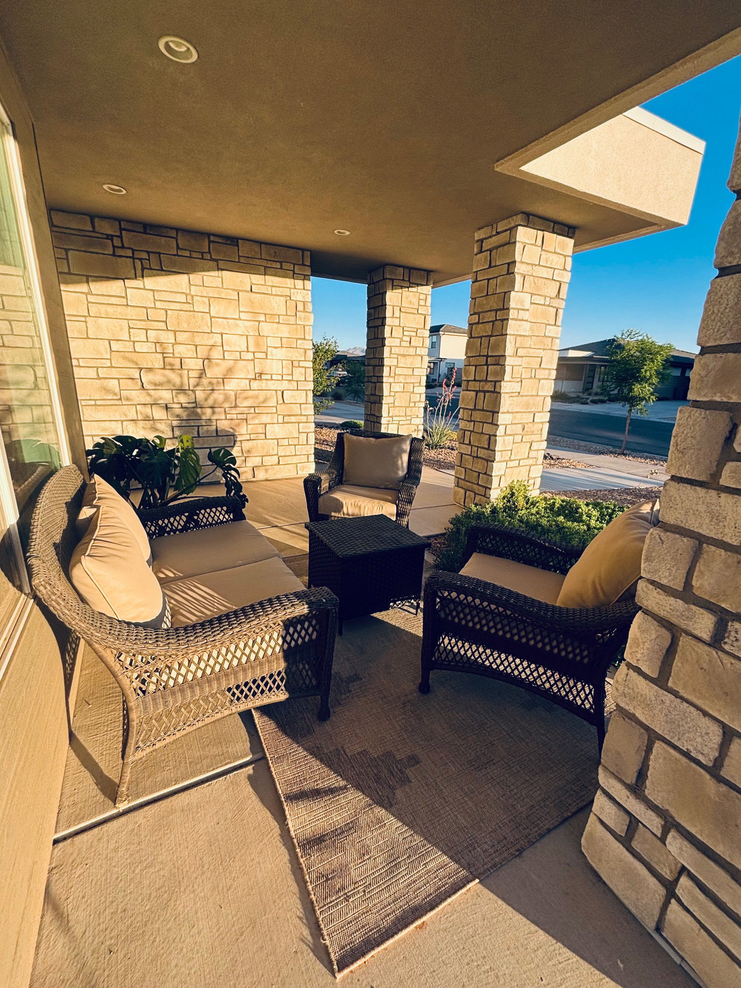 Covered patio featuring stone-clad pillars, recessed lighting, and a concrete floor