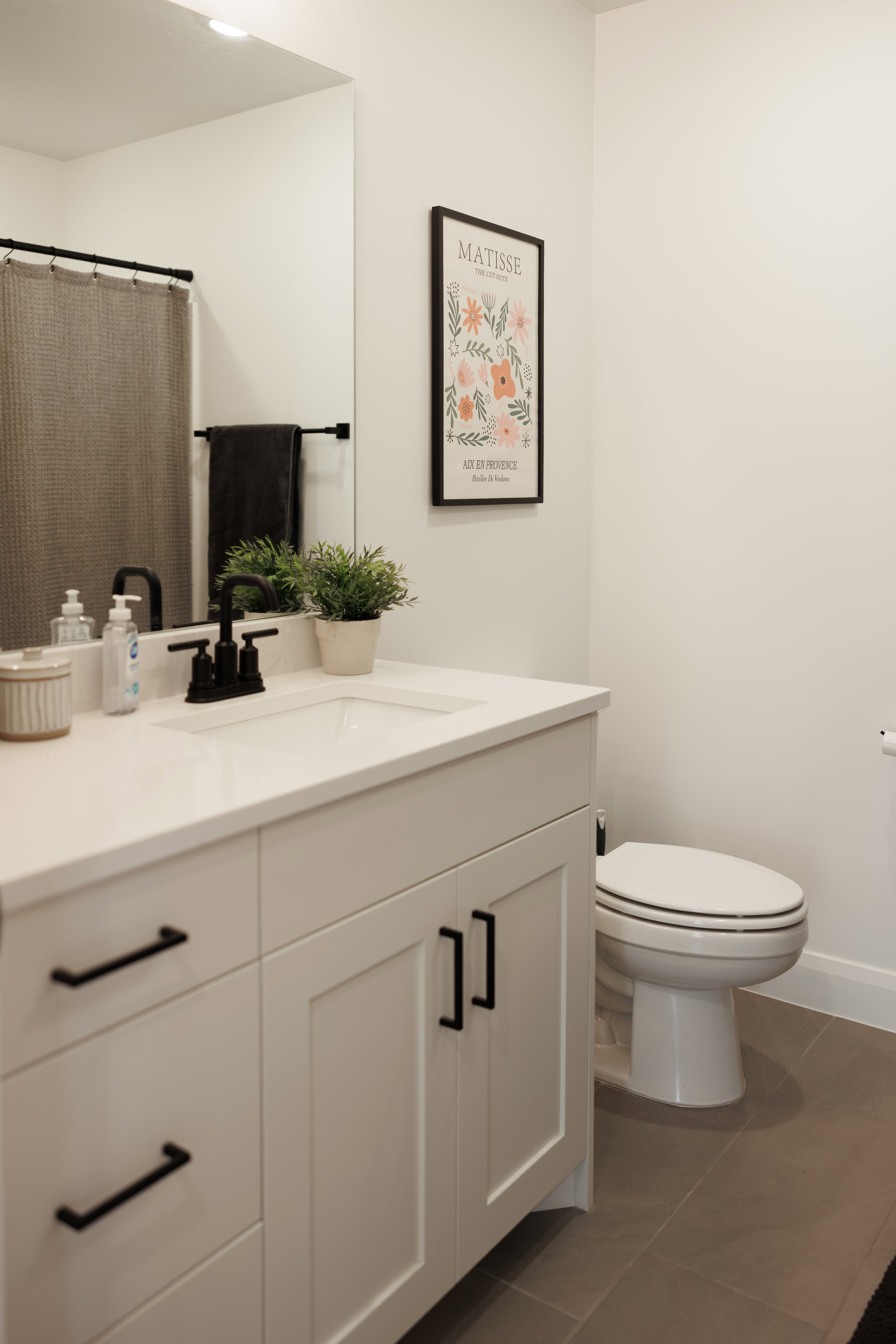 White vanity with an integrated sink, black hardware, and an overhead vanity light