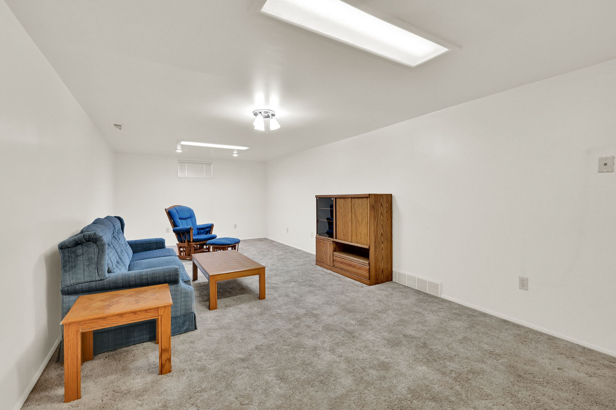 Spacious room featuring neutral carpeting, white walls, and bright overhead lighting