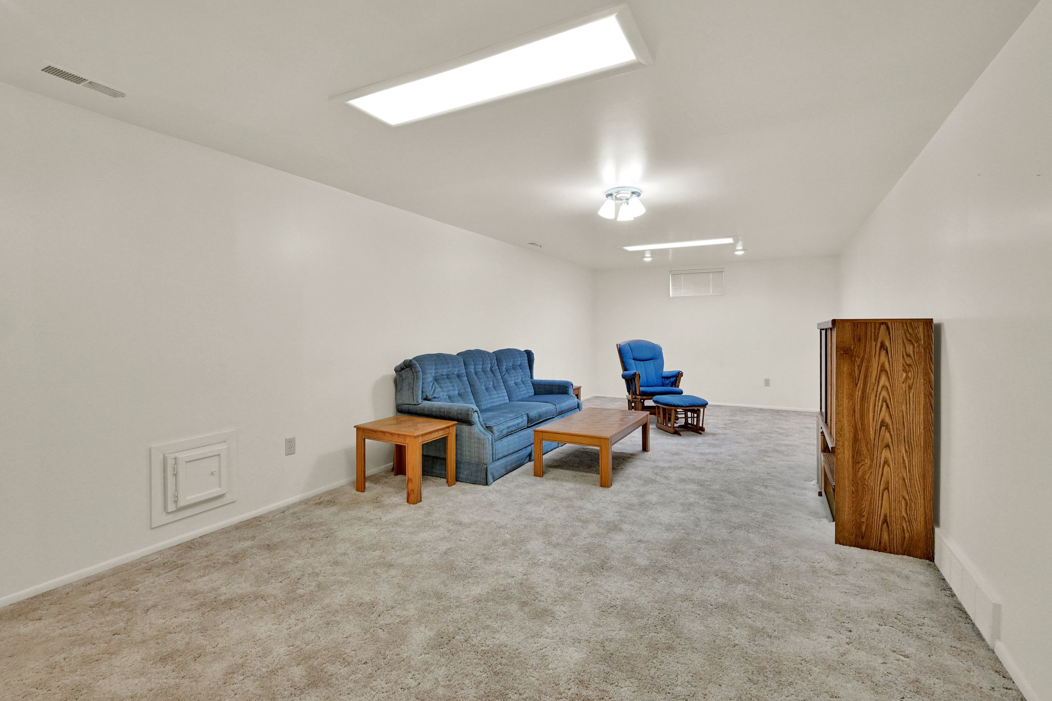 Spacious room featuring light gray carpeting, white walls, and bright overhead lighting