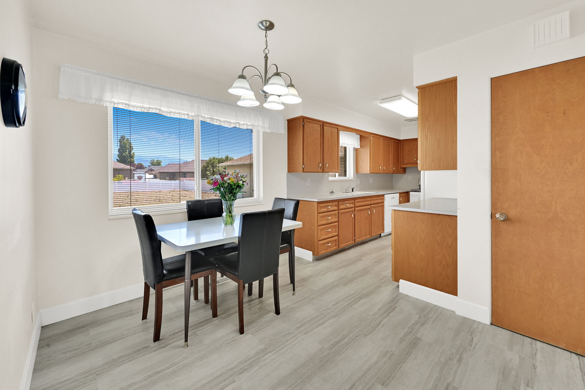 Open-concept dining area with large windows, wood-finish flooring, and a chandelier