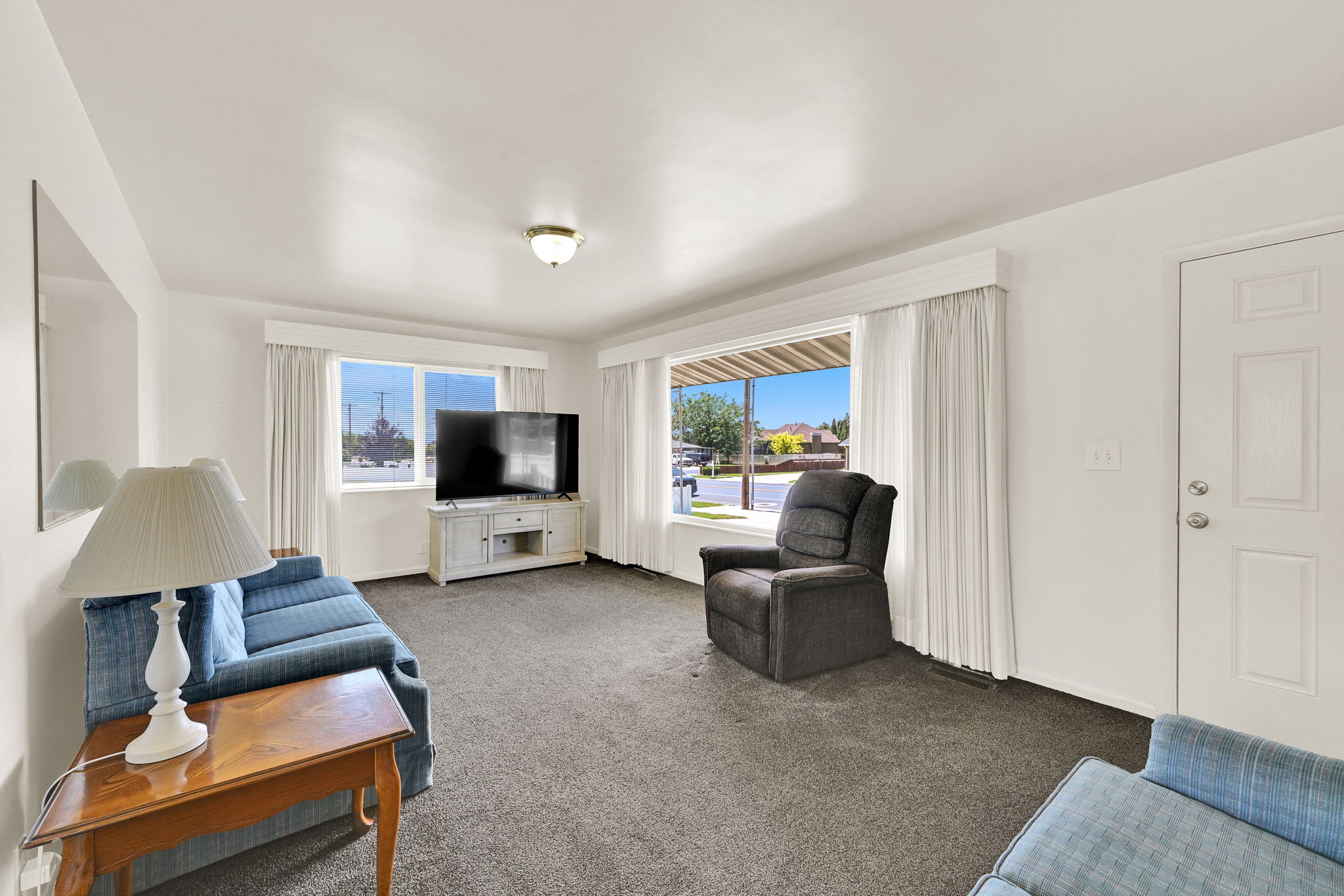 Living space featuring carpet flooring, white walls, and multiple windows