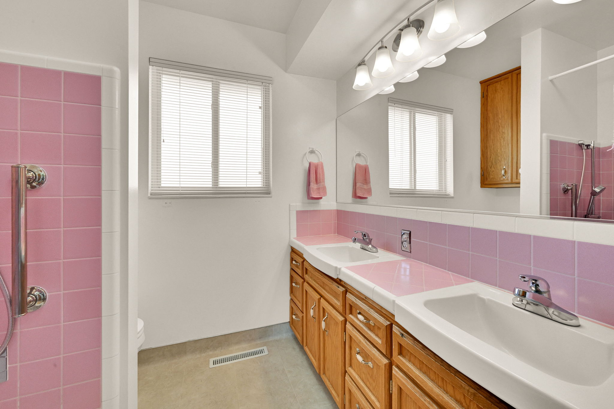 Bathroom featuring a dual vanity with oak cabinetry and integrated sinks