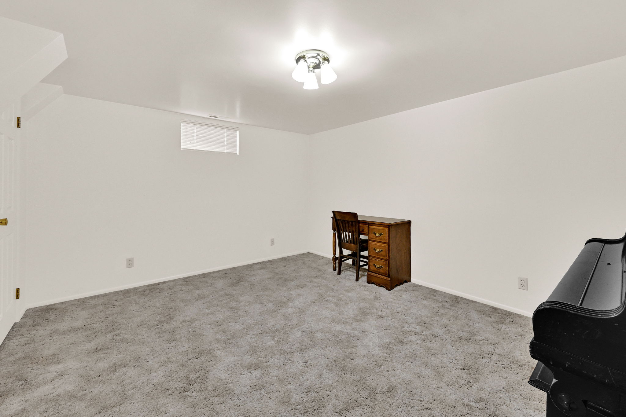 Spacious room featuring light-colored carpet flooring, white painted walls, and a semi-flush mount ceiling light fixture