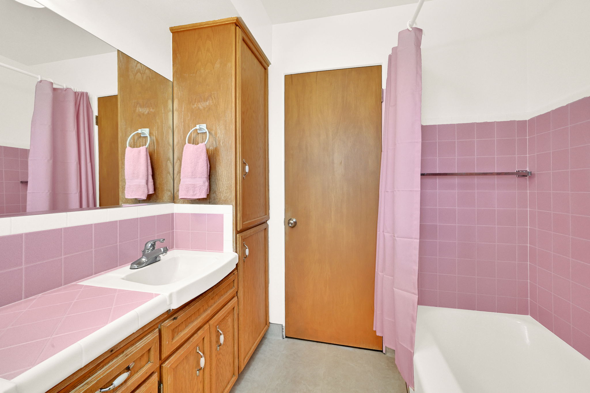 Bathroom featuring a built-in vanity with a pink tiled countertop, an integrated sink, and wood-finish cabinetry
