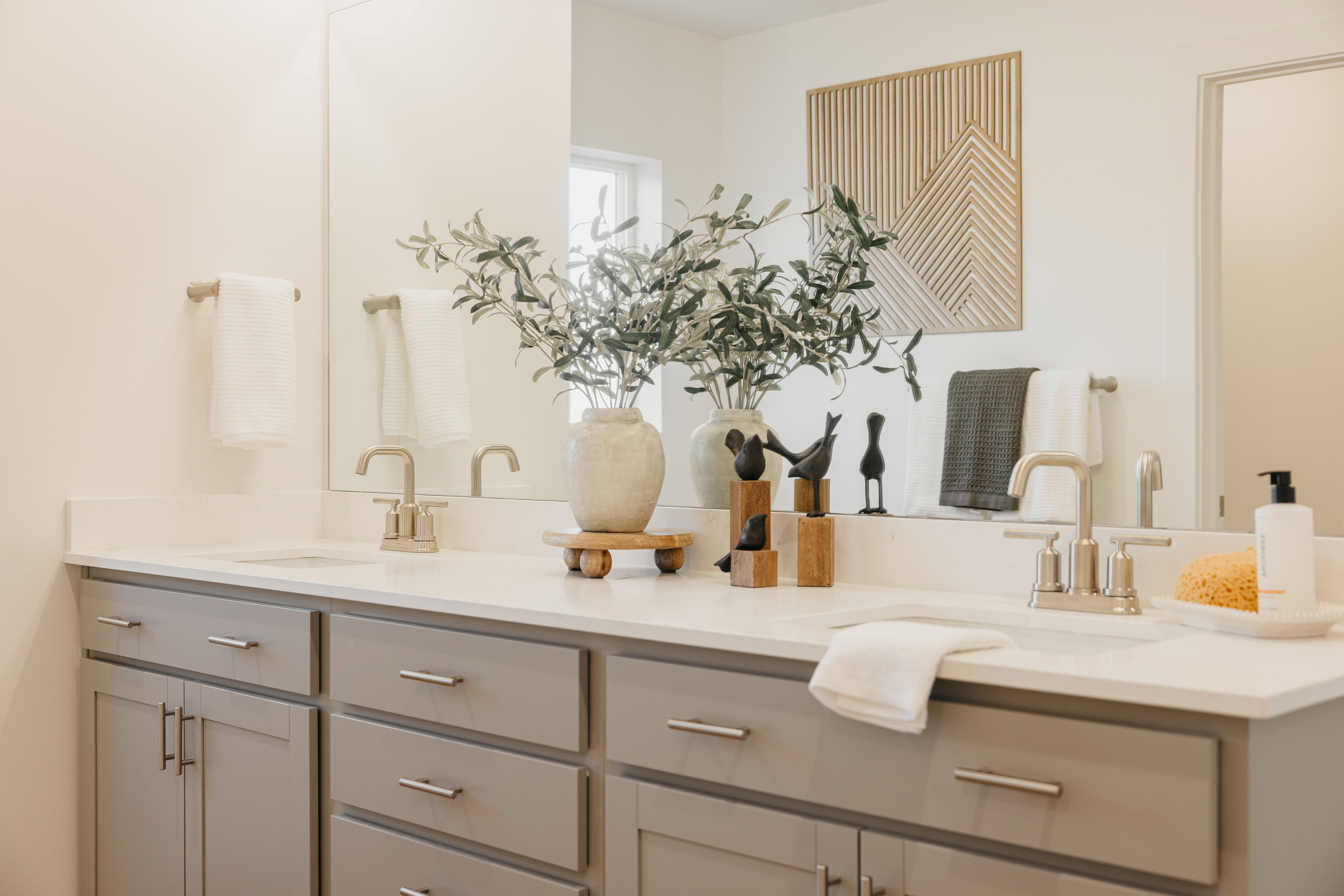 Double vanity featuring light gray cabinetry with brushed nickel hardware, white countertops, and dual undermount sinks with brushed nickel faucets