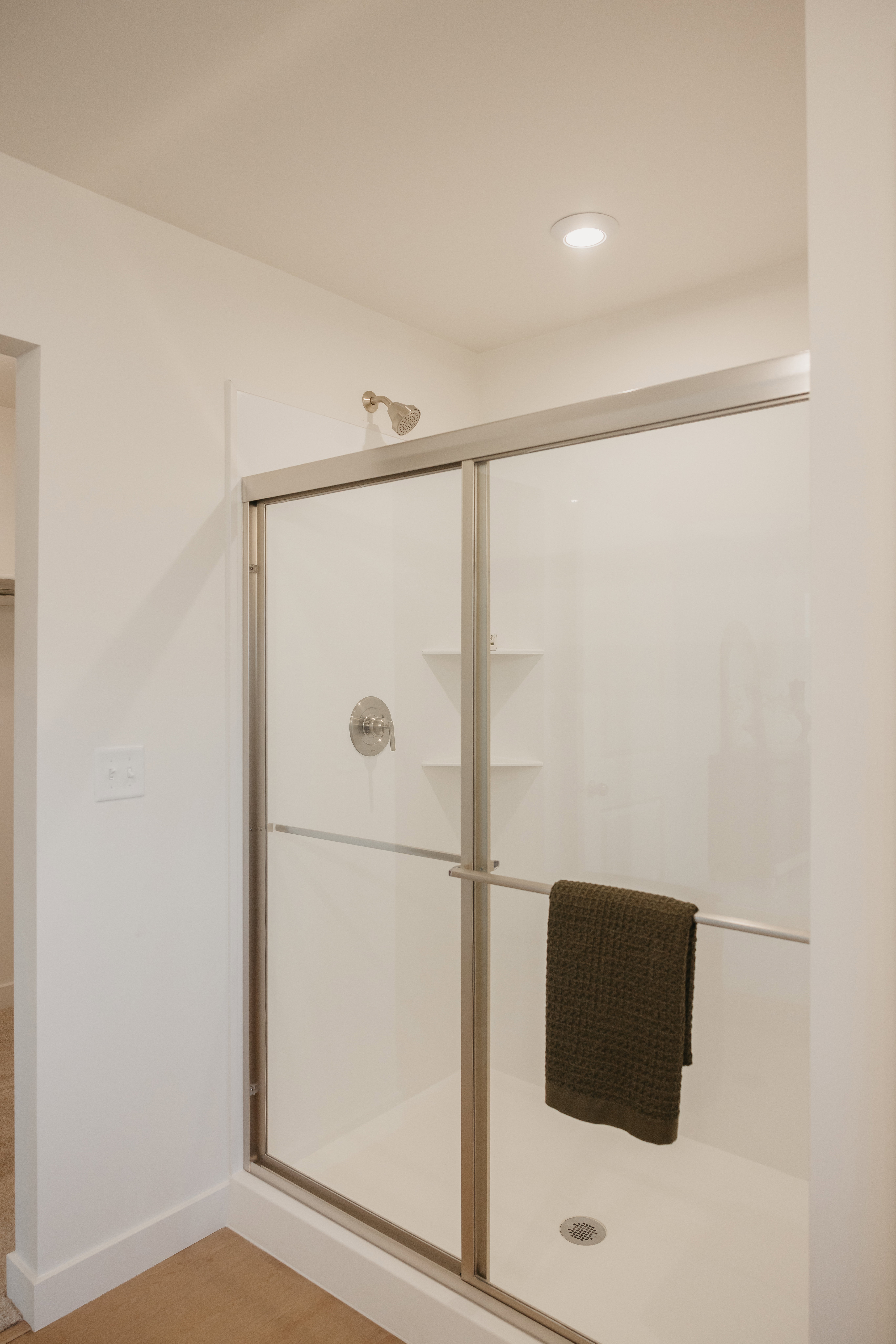 Glass-enclosed shower featuring a brushed nickel showerhead and control valve