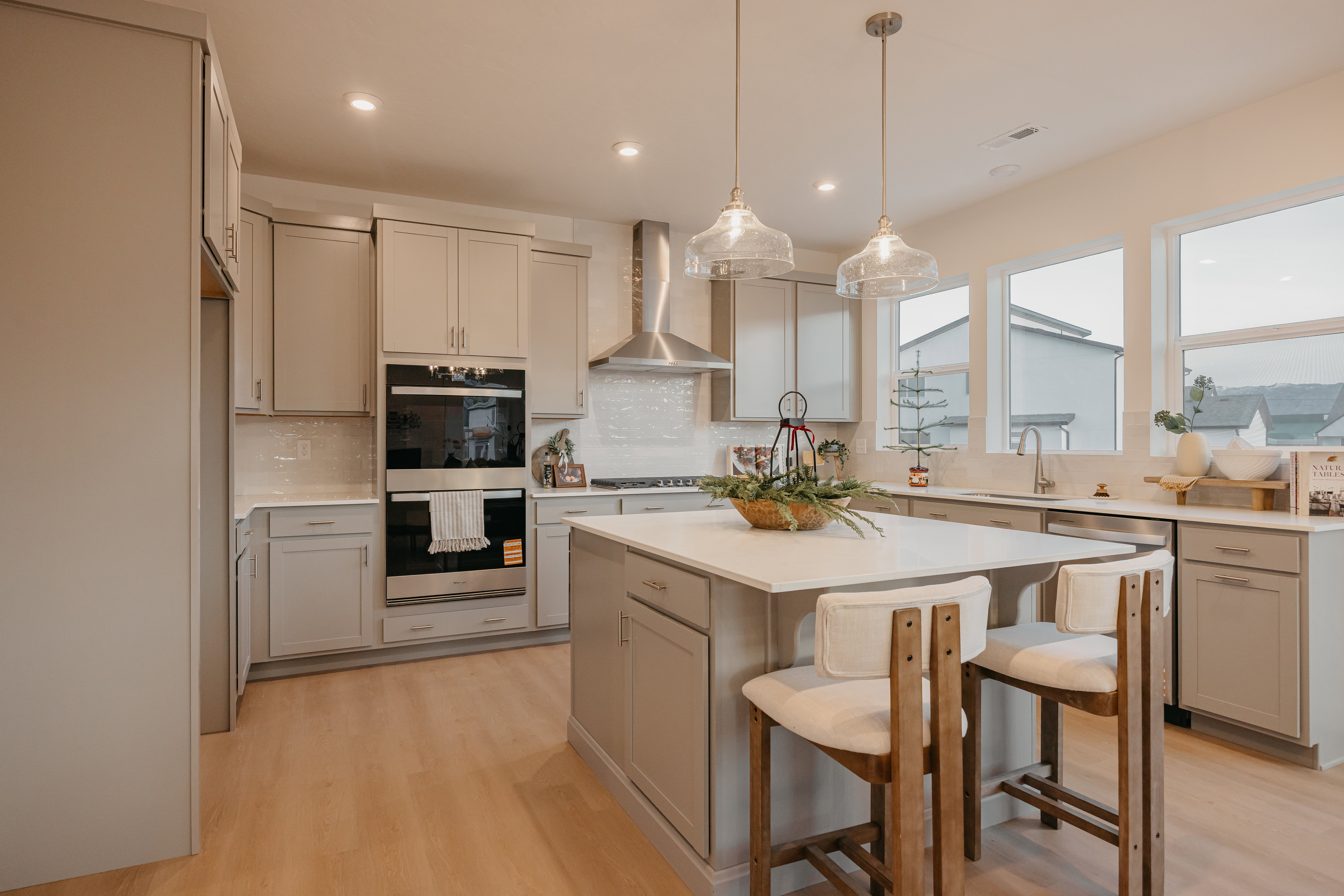 Modern kitchen featuring light wood-finish flooring, light gray cabinetry, and a white tile backsplash
