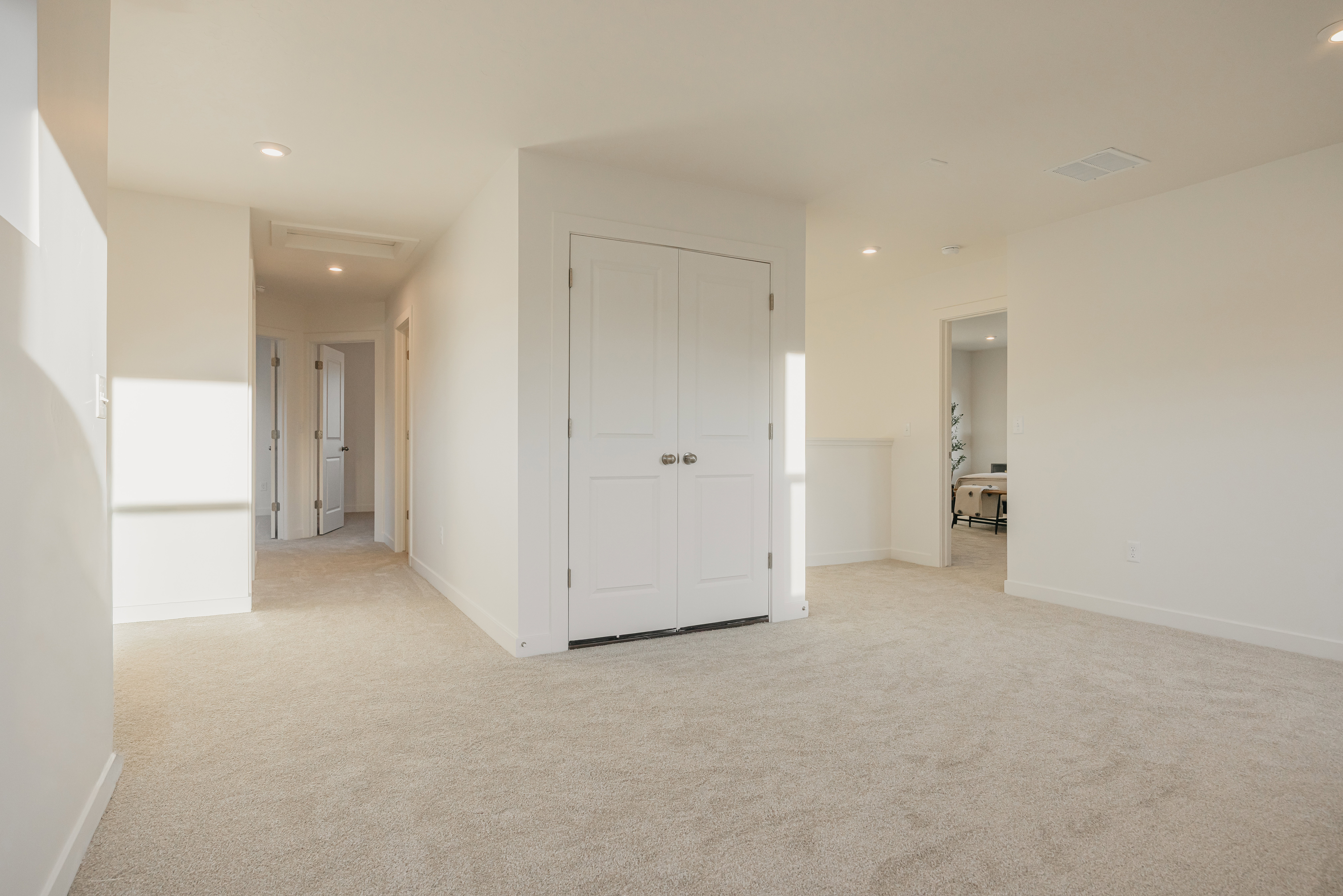 Spacious carpeted area with recessed lighting, white walls, and bright white trim