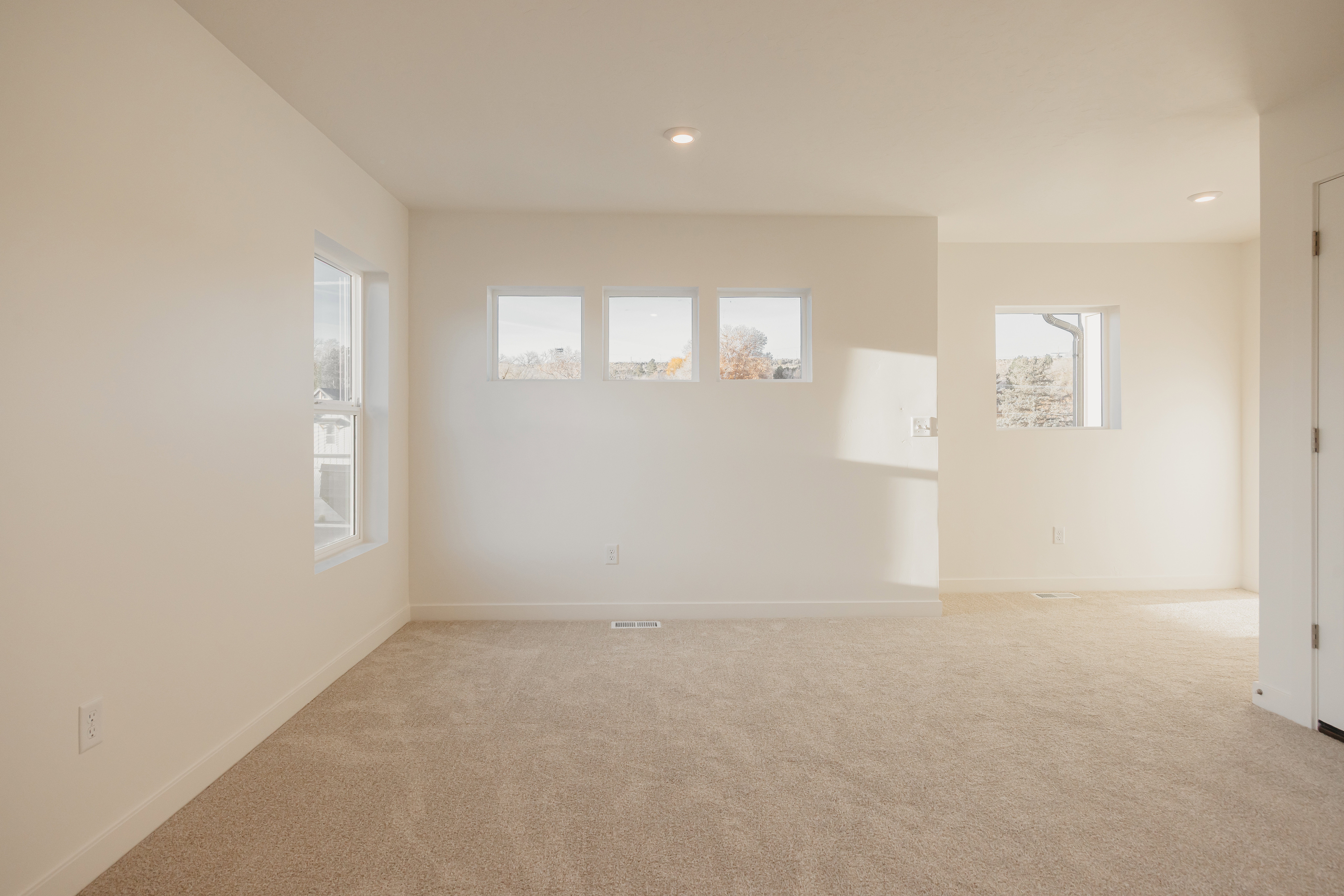Neutral-toned carpeting throughout a room with recessed lighting