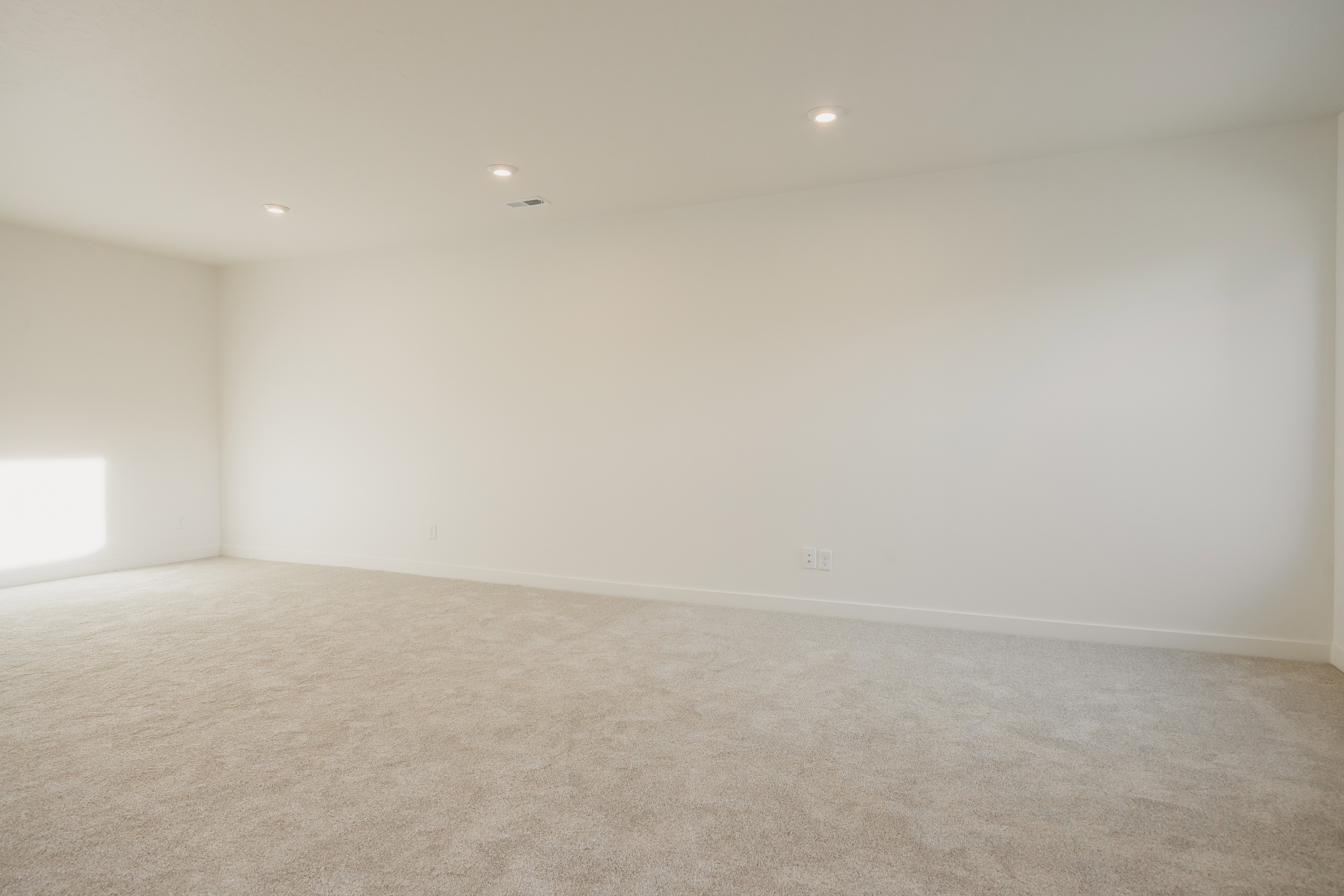 Spacious room featuring neutral carpeting, recessed ceiling lighting, and a soft neutral wall color