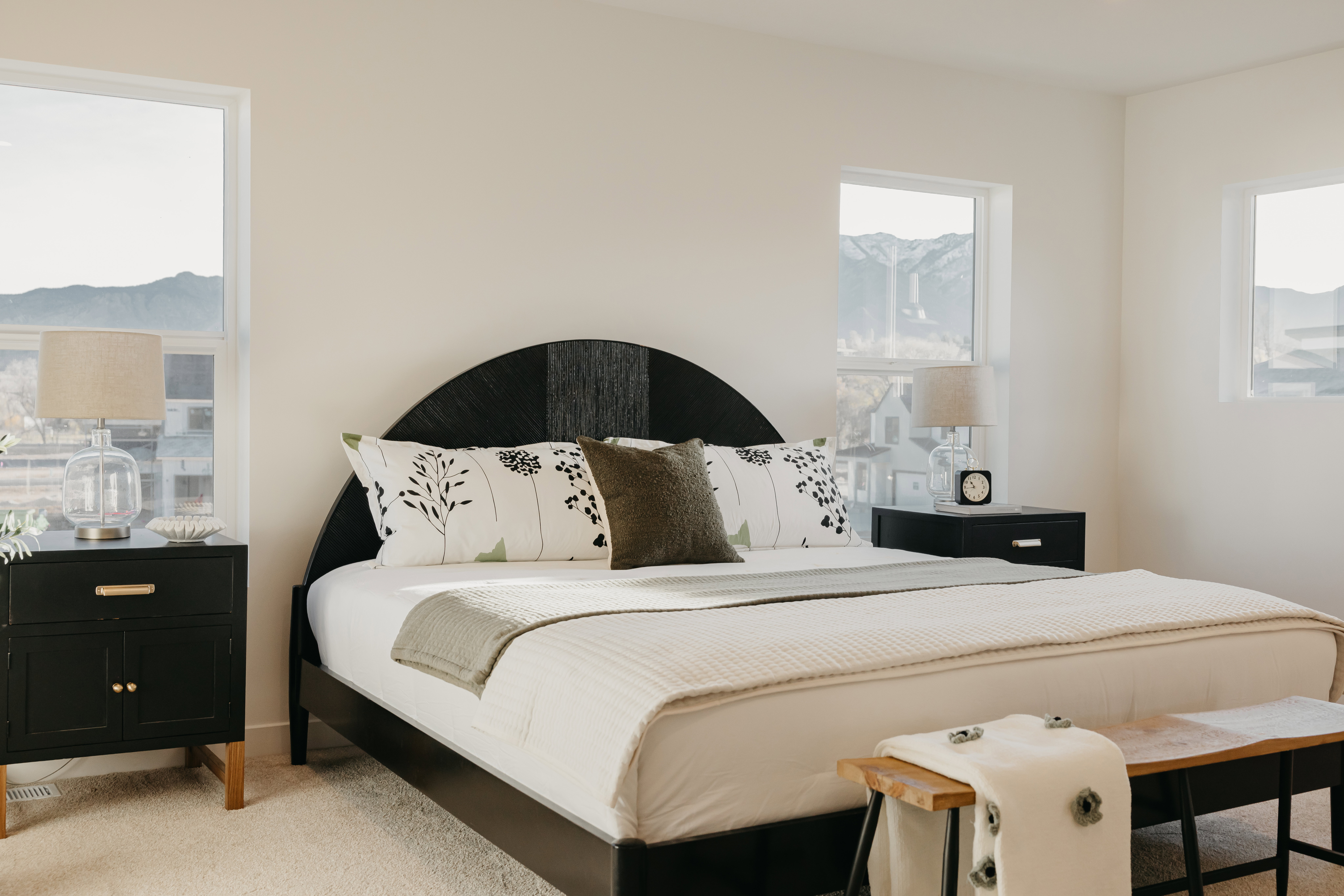 Light-filled room featuring multiple windows with mountain scenery, neutral wall tones, and plush carpeting