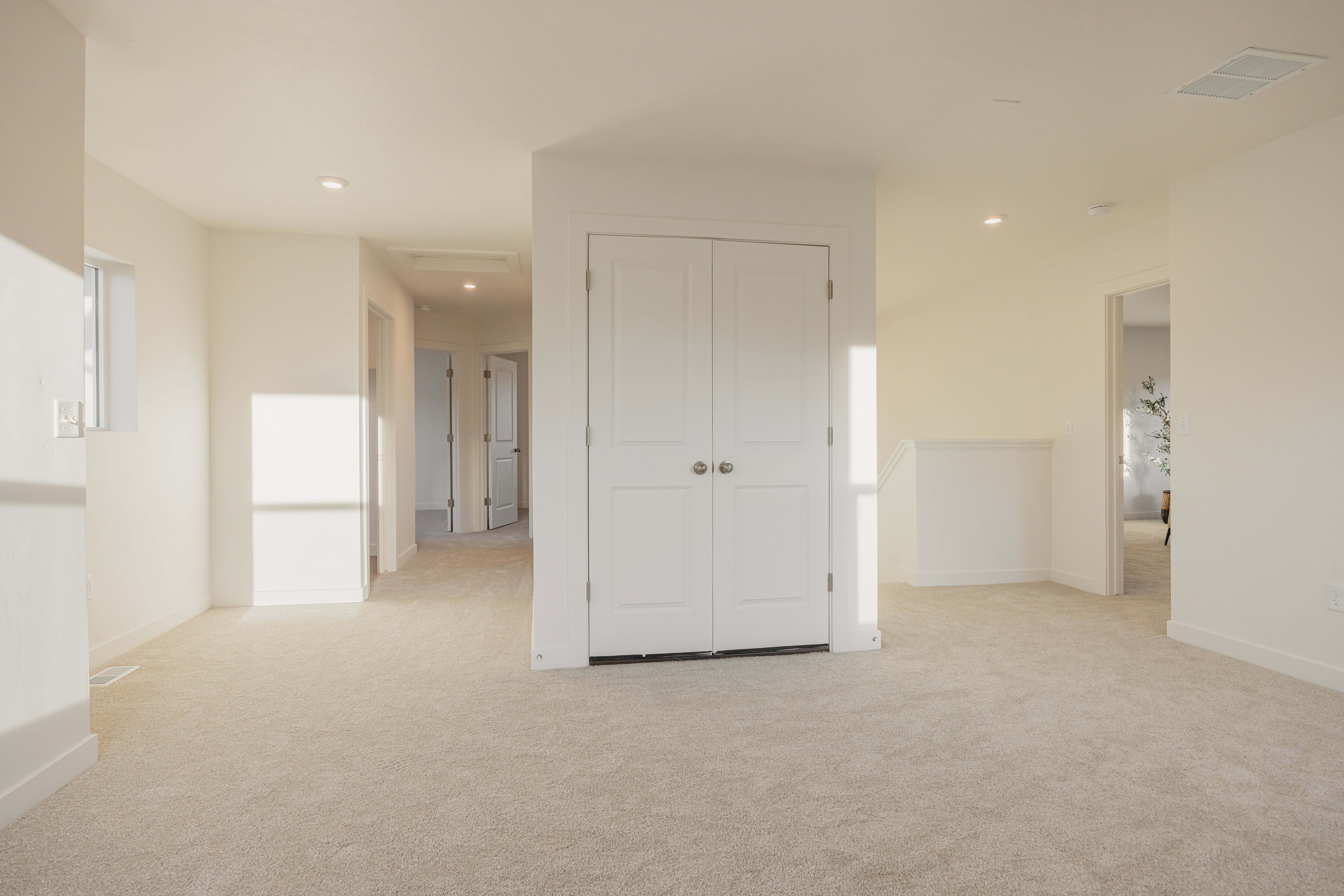 Expansive carpeted area featuring recessed lighting, a window, and multiple doors with white trim
