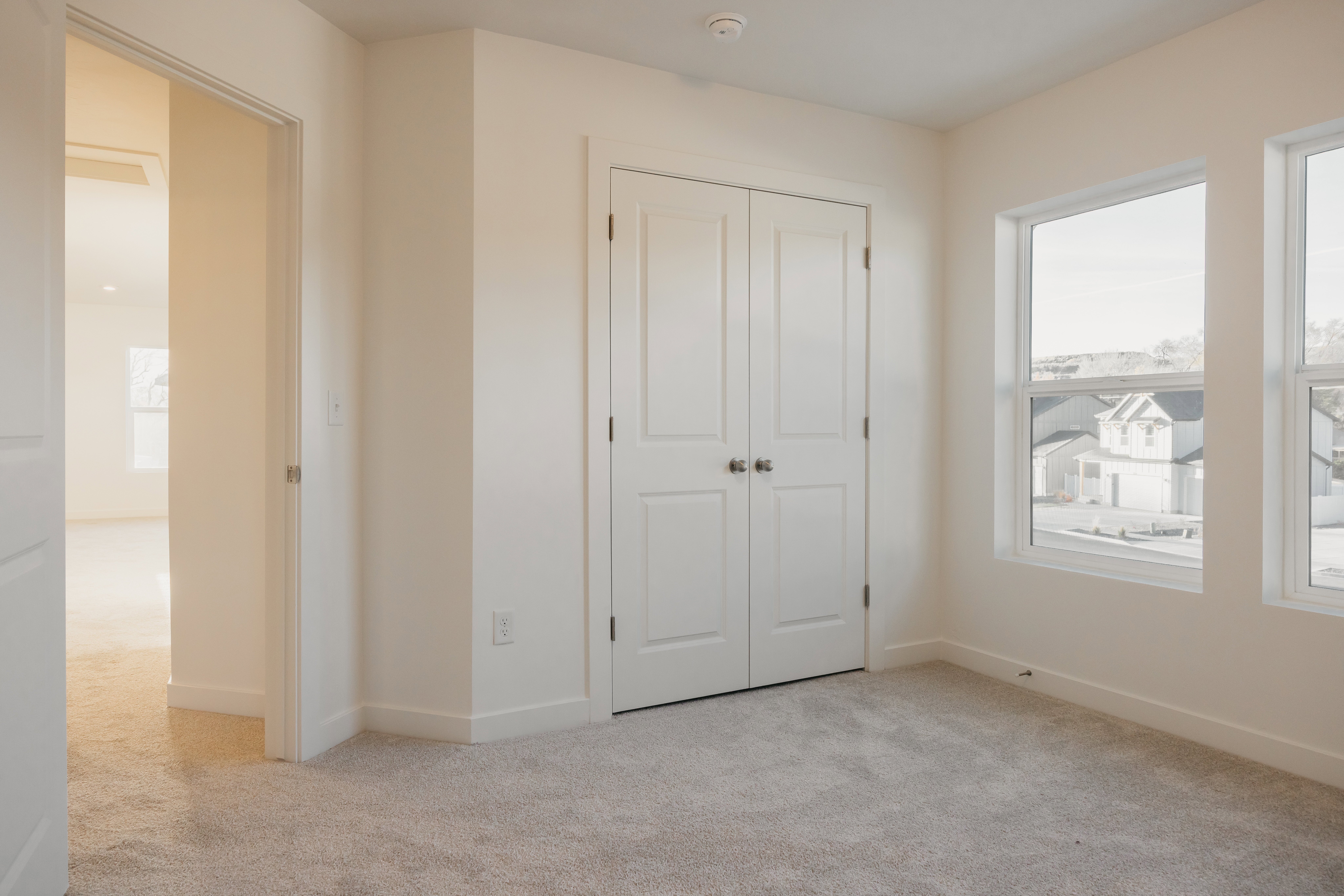 Room featuring soft gray carpeting, white walls, and a double-door closet with dark hardware