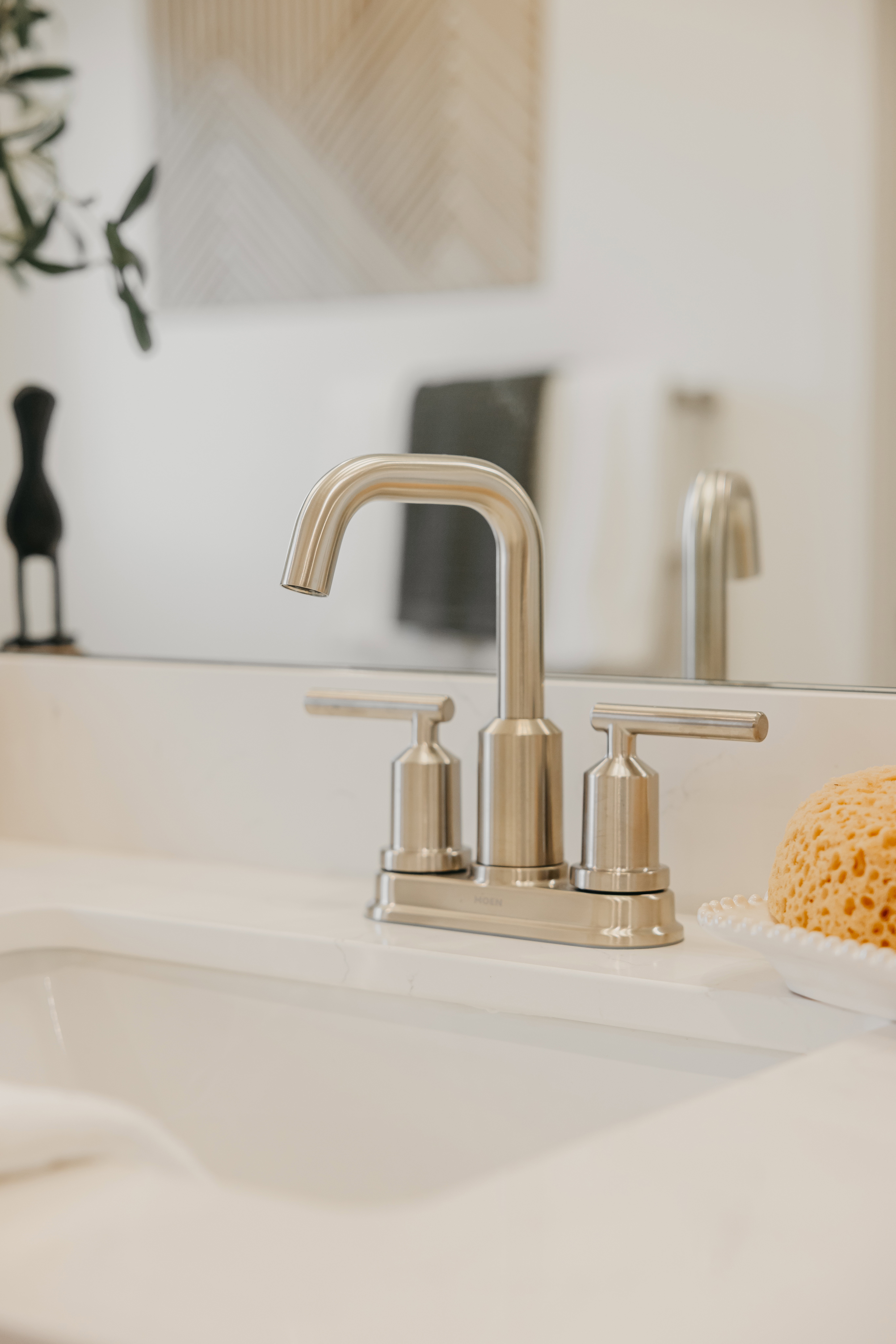 Sleek brushed nickel faucet fixture with double handles, set into a crisp white countertop and integrated sink