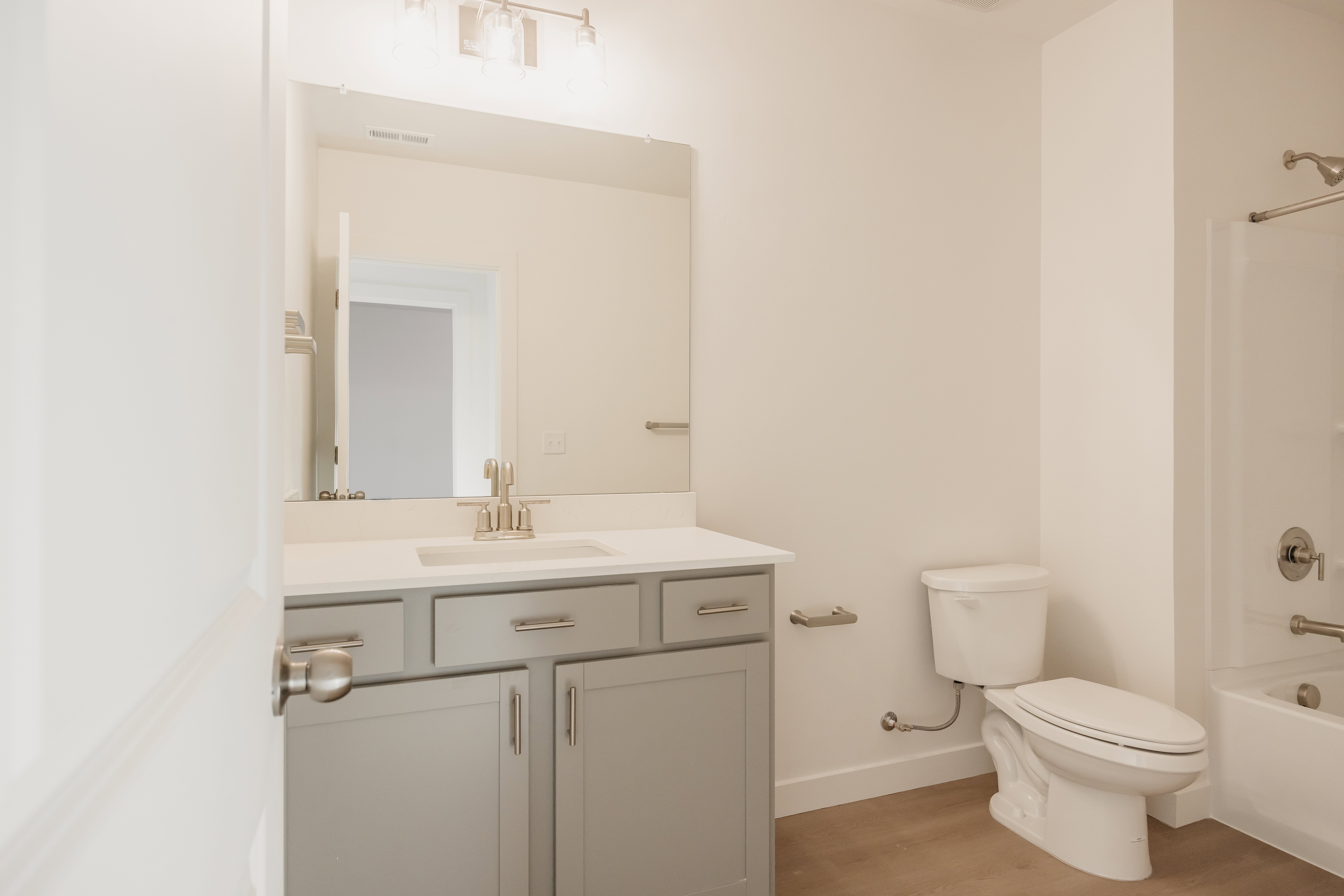 Bathroom featuring a light gray vanity with brushed nickel hardware, a white countertop, a rectangular undermount sink, and a chrome faucet