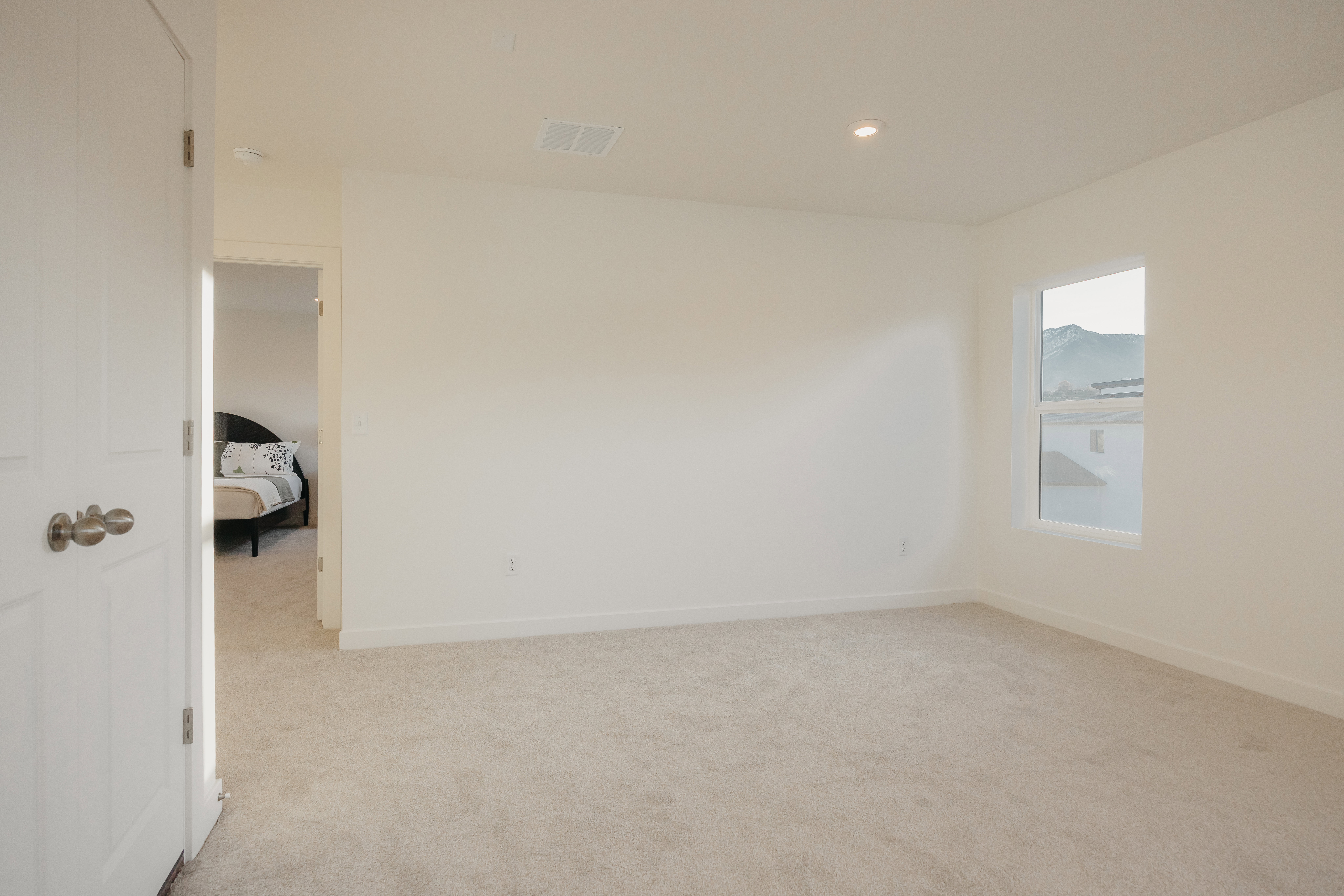 Spacious room featuring neutral carpeting, white walls, a single window, and a recessed ceiling light