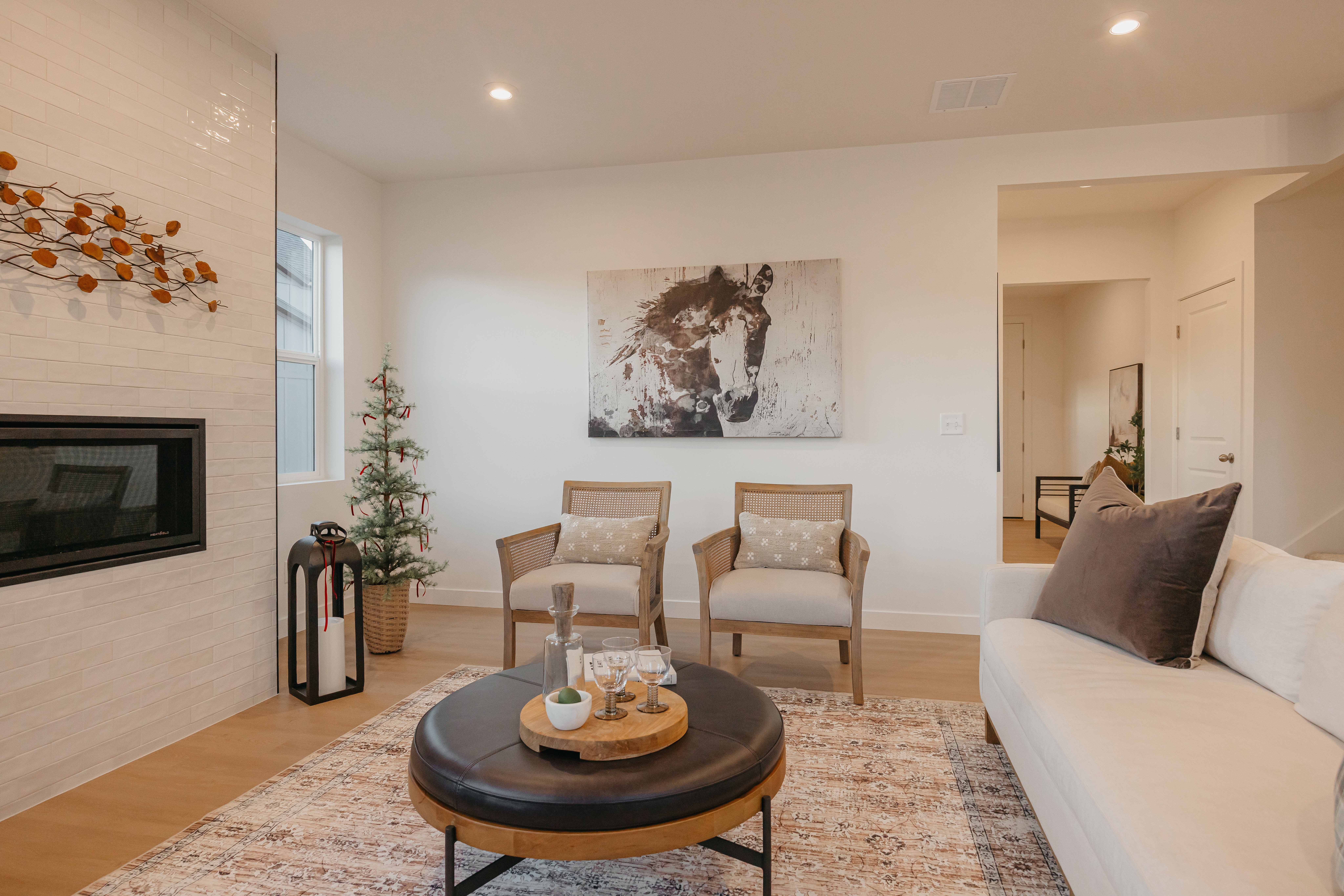 Open-concept living space featuring wood-finish flooring, a contemporary fireplace with a tiled surround, recessed lighting, and a white baseboard trim