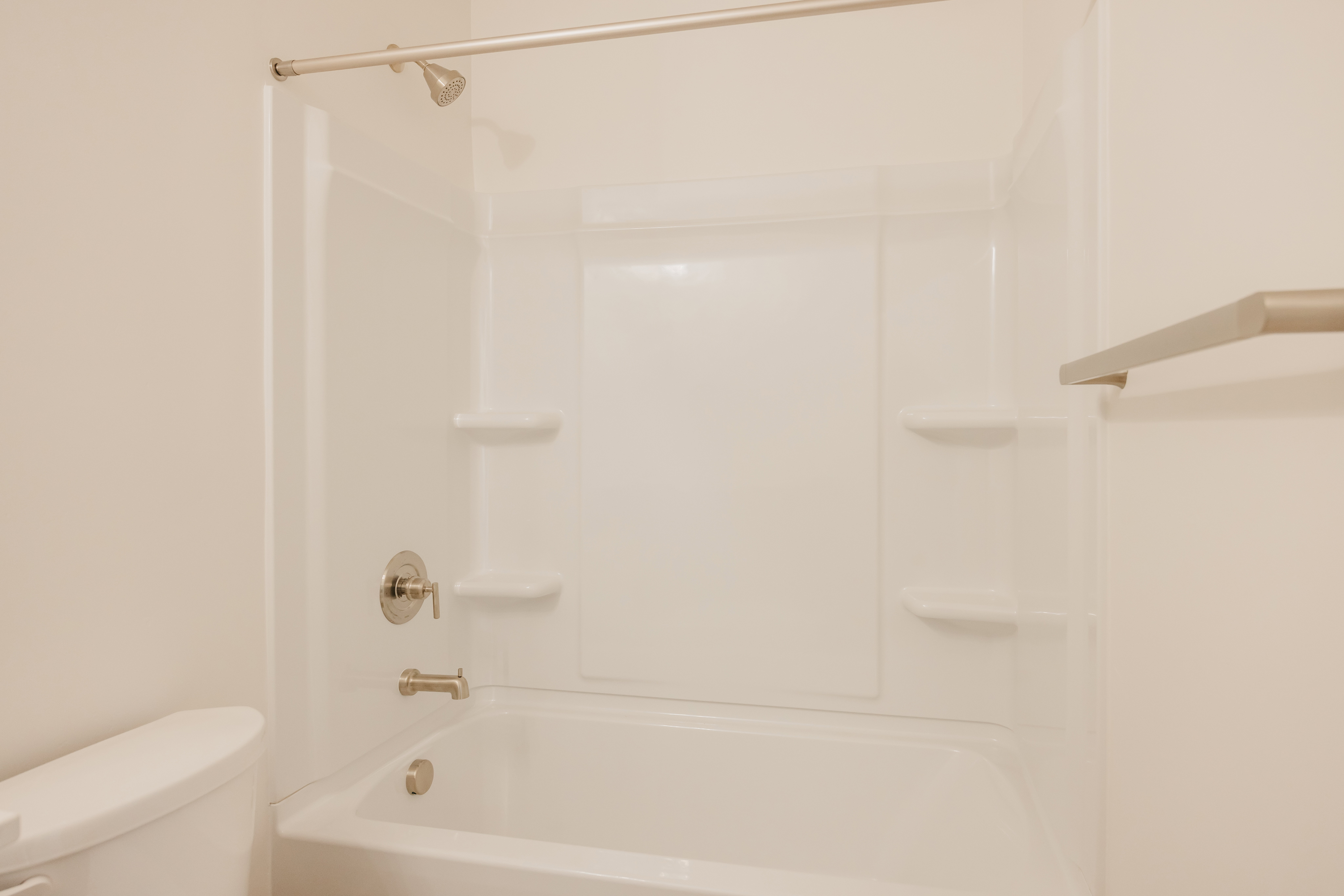 White fiberglass tub and shower combination featuring integrated shelving