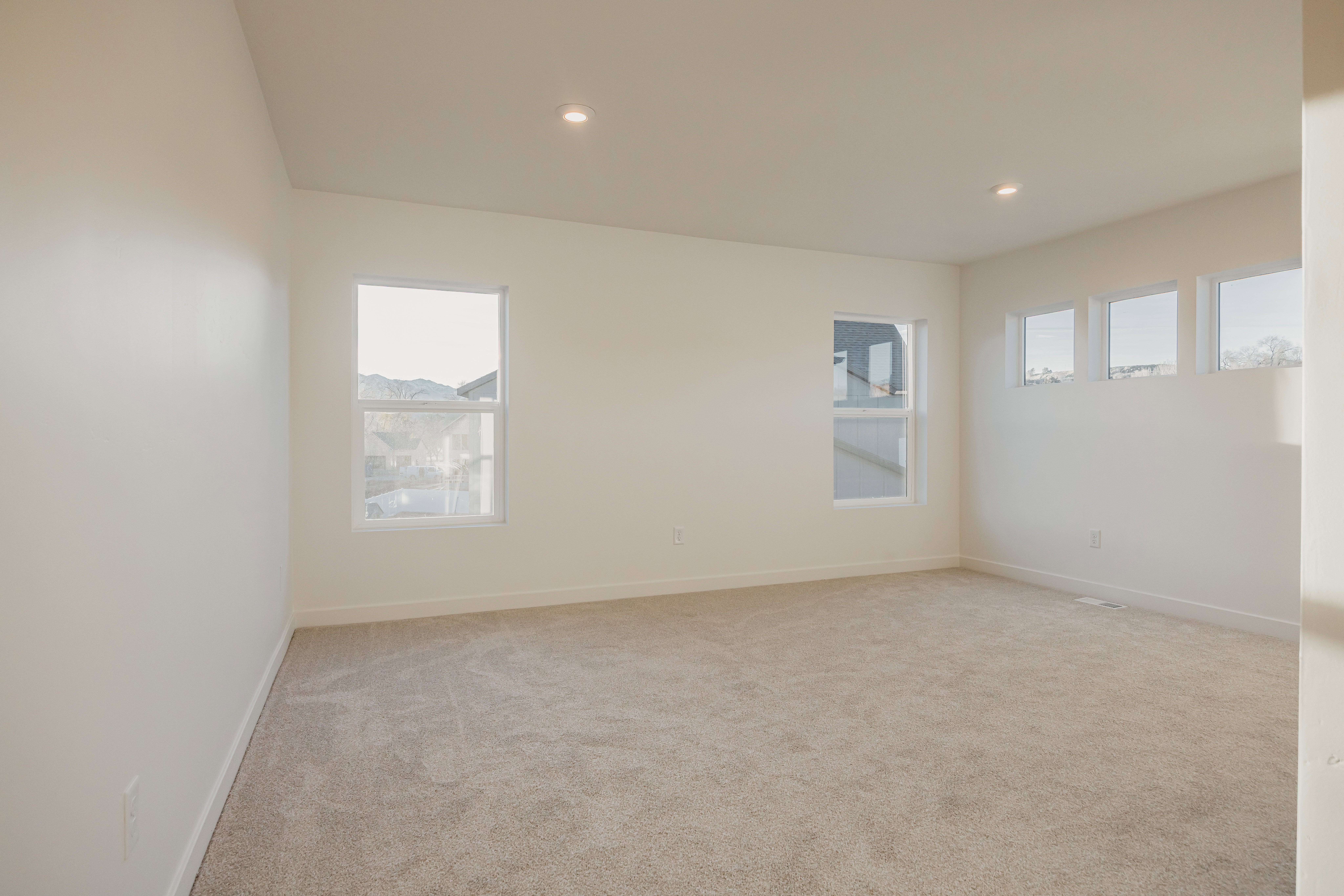 Spacious interior room featuring light-toned walls and neutral carpeting