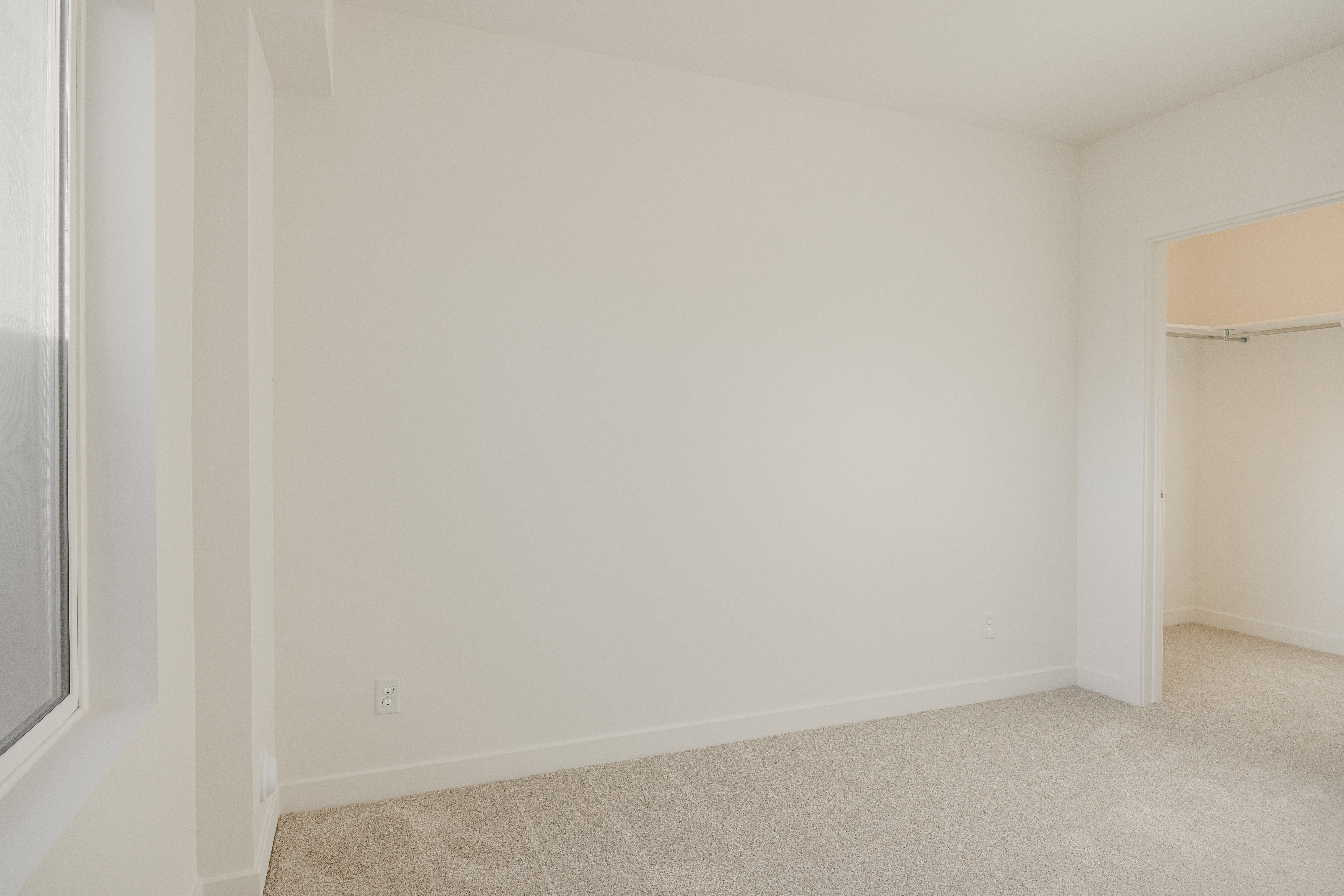 Room featuring light-colored carpeting, white walls, and a white trim baseboard