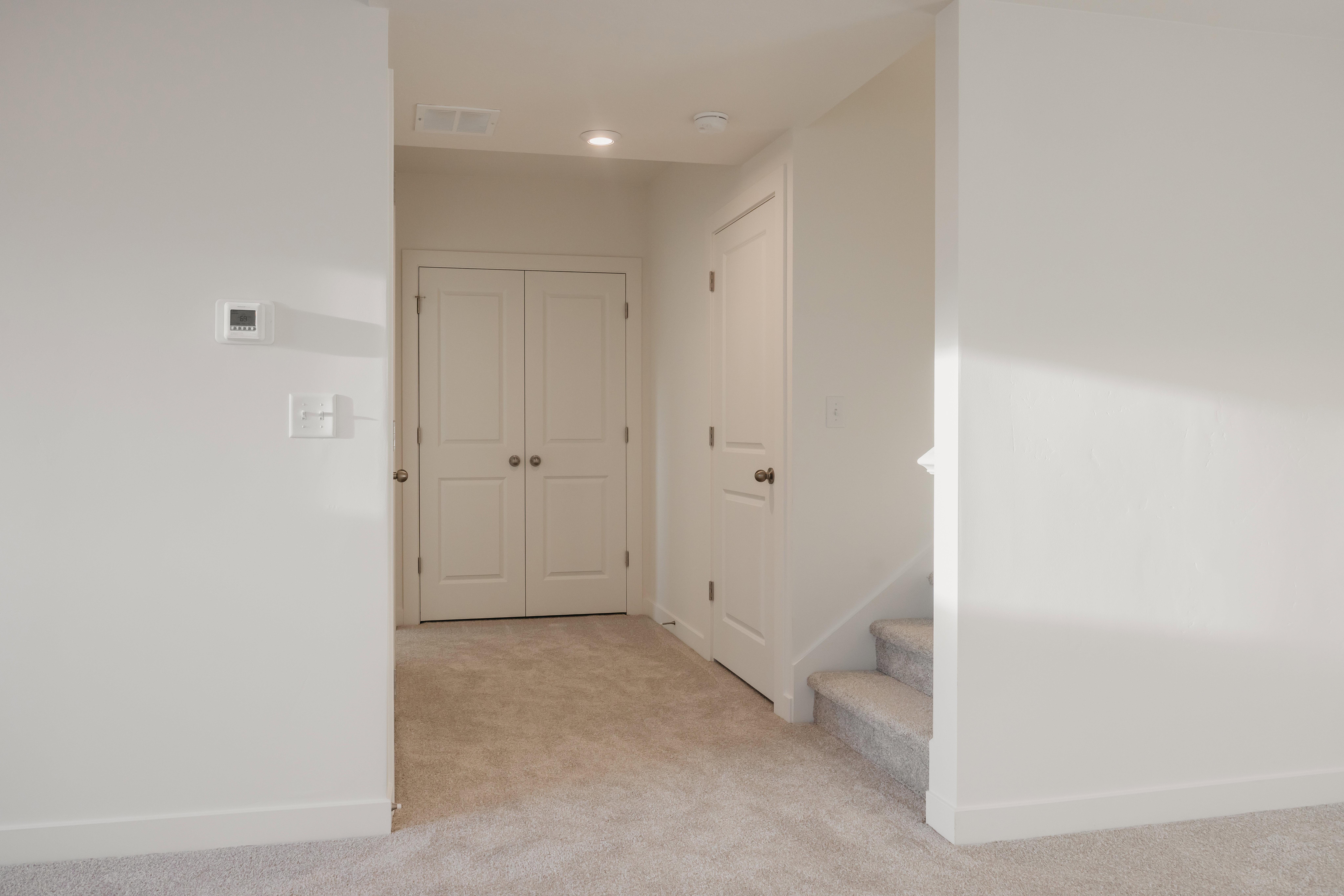 Hallway featuring light-toned carpet flooring, white walls, white trim, and recessed lighting
