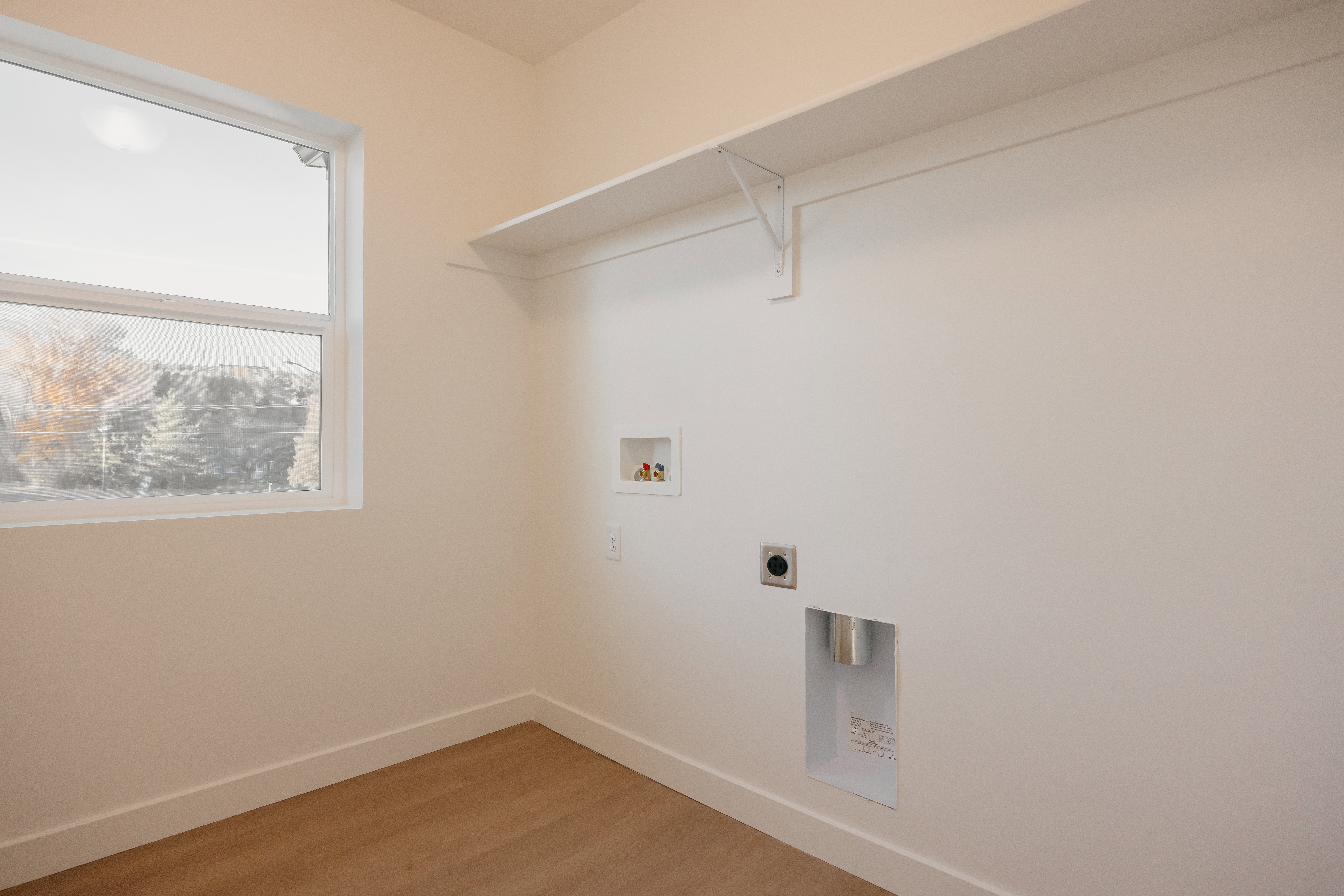 Utility room featuring a window, wood-finish flooring, and a built-in shelf