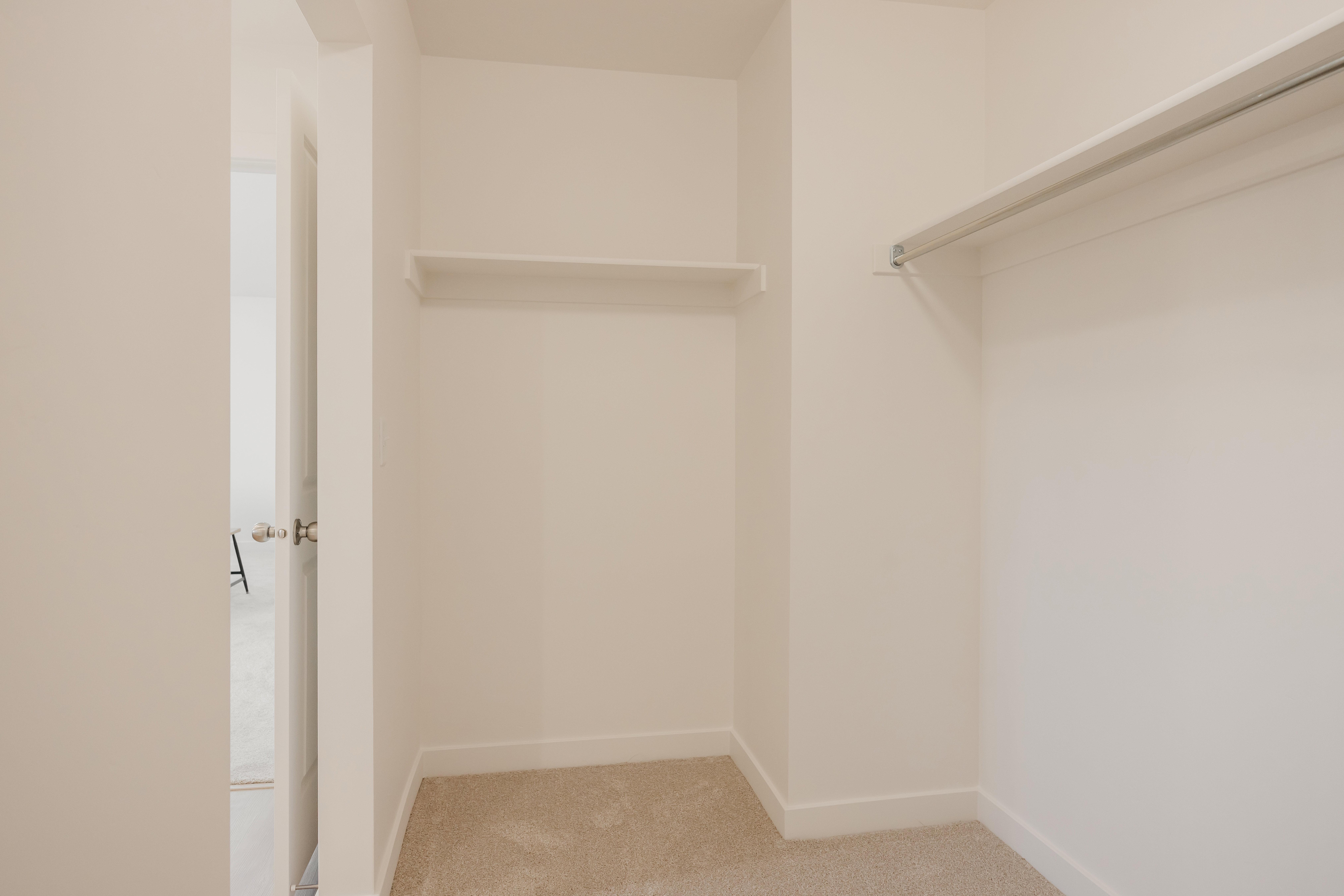Built-in shelving and hanging rods with neutral carpeting and white trim